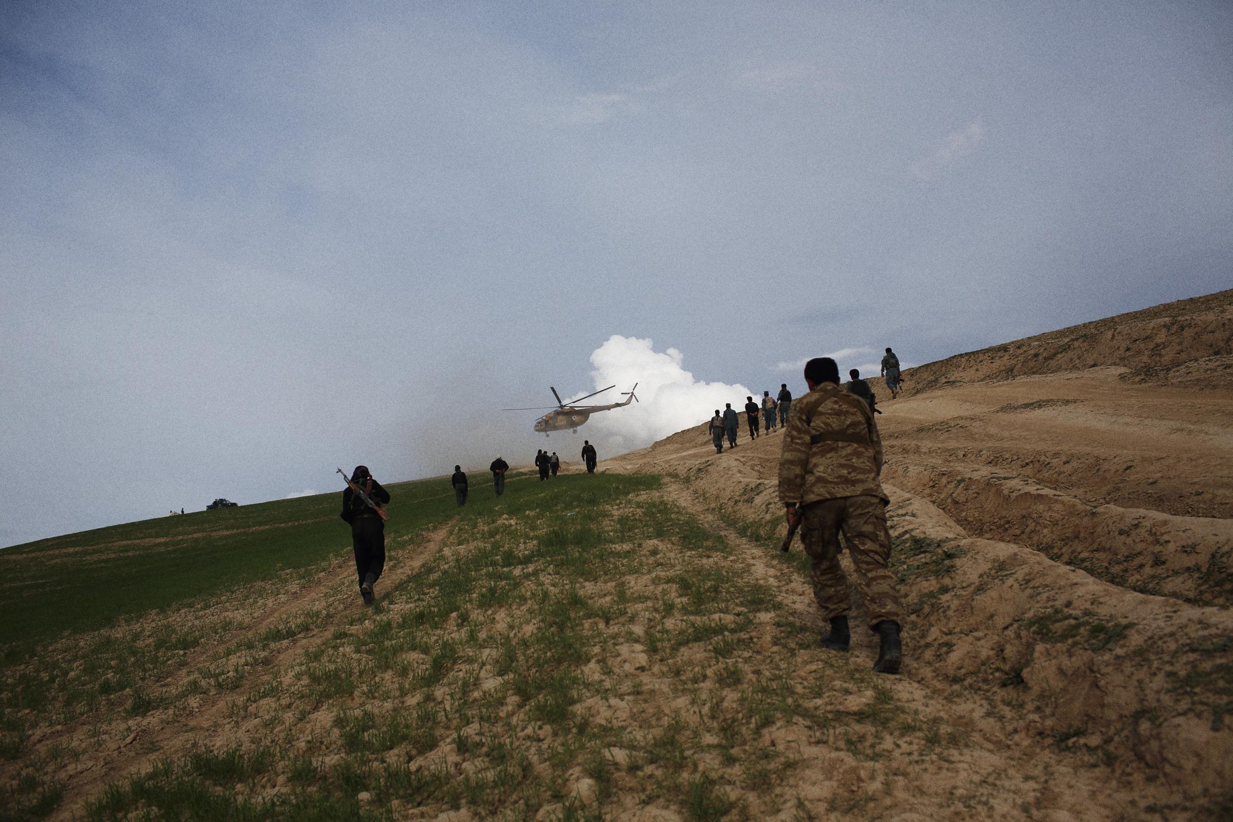 Police climb a hill to guard a helicopter aid delivery, May 6, 2014.