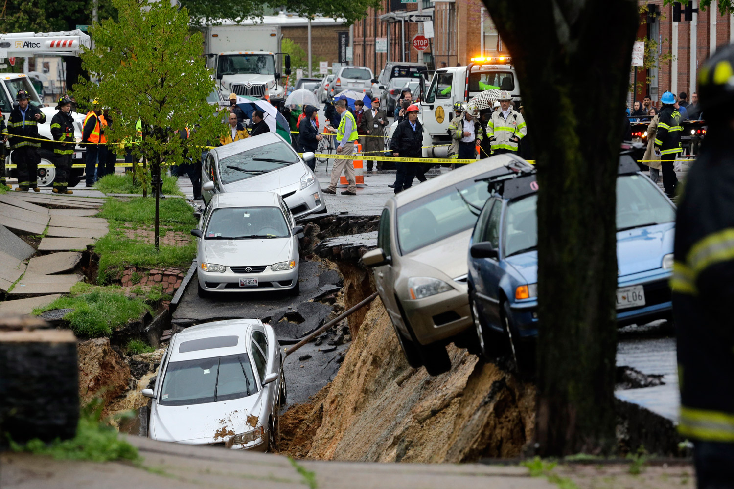 Cars sit on the edge of a sinkhole in the Charles Village neighborhood of Baltimore, April 30, 2014, as heavy rain moves through the region. (AP)
