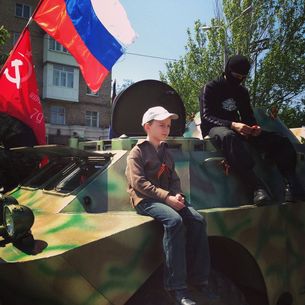 May 10, 2014. A child and a fighter from the self-proclaimed Donetsk People's Republic sit atop an armored personnel carrier in Donetsk, Ukraine.