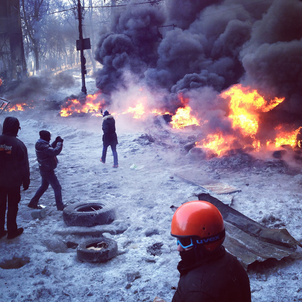 January 25, 2014. Following the end of a short-lived ceasefire during an anti-government protest, onlookers watch tires burn in Kyiv, Ukraine.