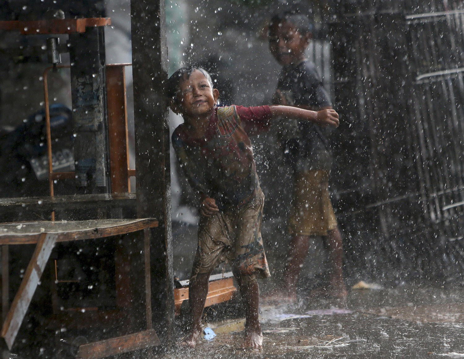 Indonesian children play in the rain during a heavy downpour in Jakarta on May 28, 2014.