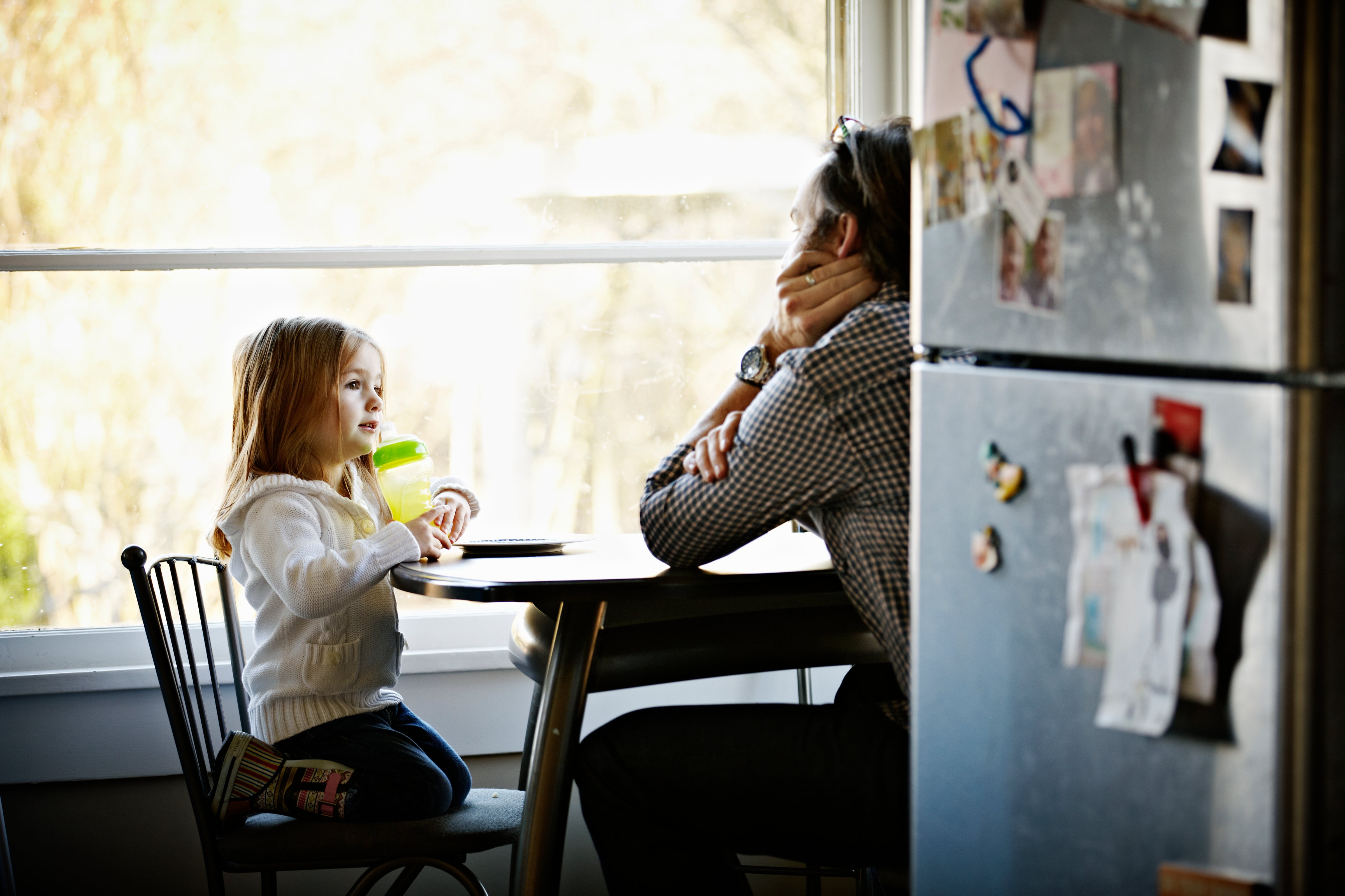 Father and daughter sitting at table in kitchen