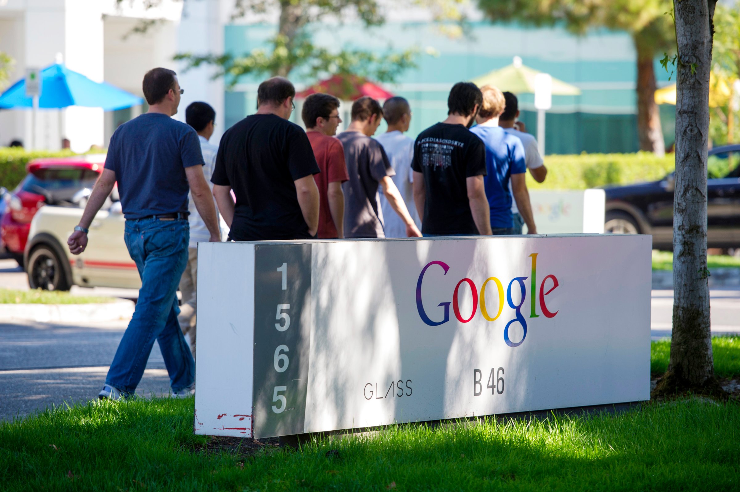 Pedestrians walk past Google Inc. signage displayed in front of the company's headquarters in Mountain View, Calif. on Sept. 27, 2013.