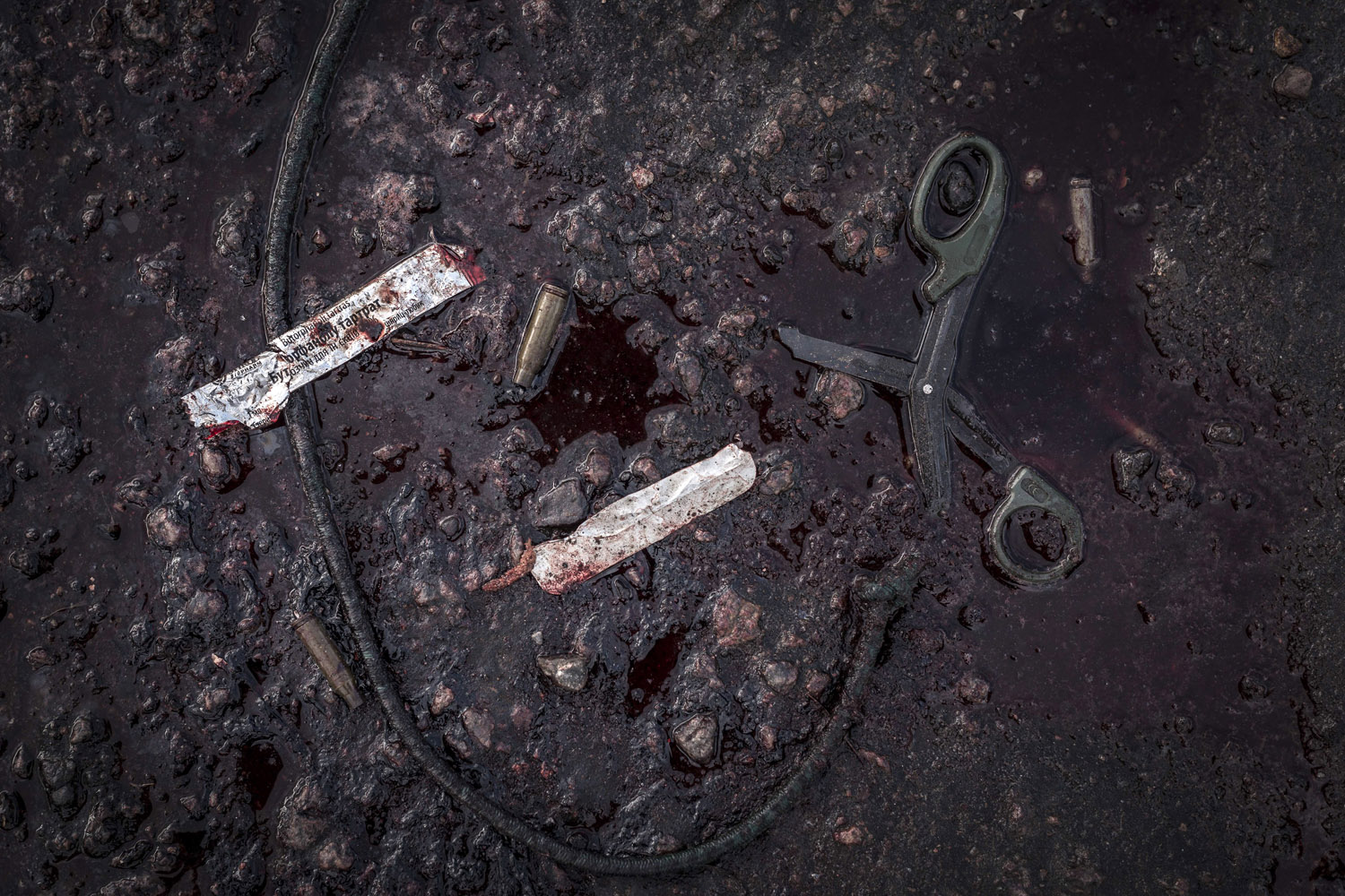Bullet casings, scissors and the wrapper to a tourniquet lie in a puddle of blood on the outskirts of Slovyansk, eastern Ukraine.