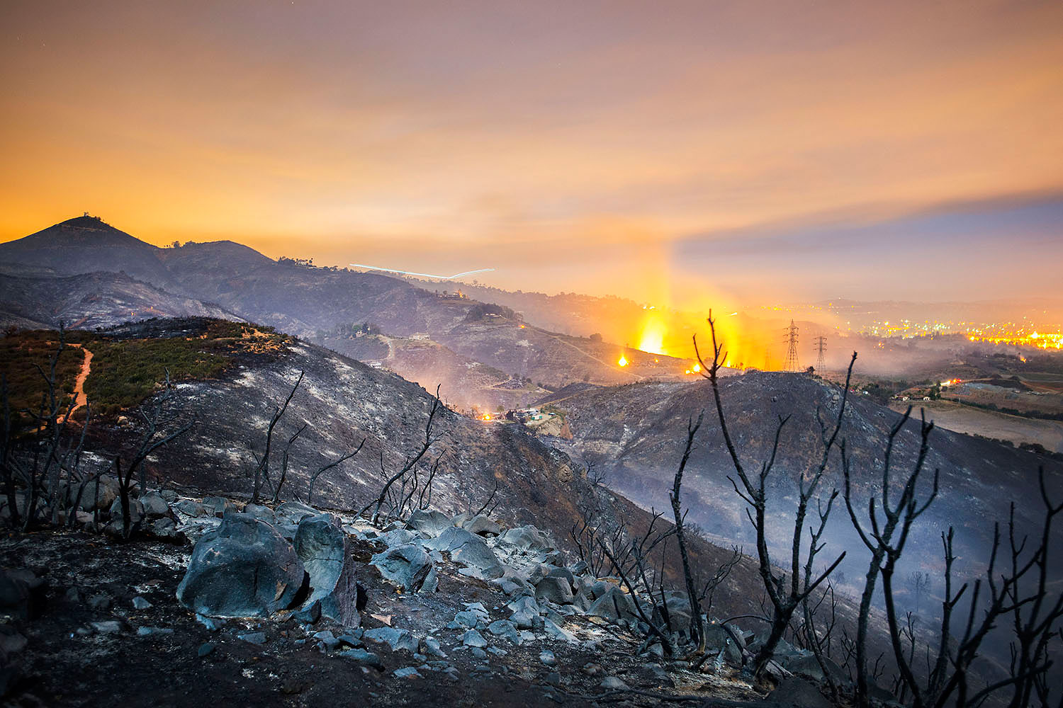 A longtime exposure shows smolderings remains of overnight fires on the hillsides of San Marcos, San Diego county, Calif., May 16, 2014.