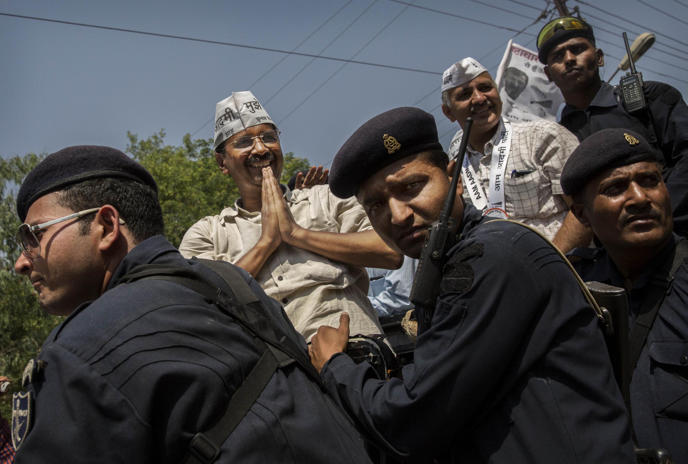 AAP leader and anti-corruption activist Arvin Kejriwal is surrounded by police bodyguards as he greets supporters from an open jeep on his way to file his nomination papers on April 23, 2014 in Varanasi.