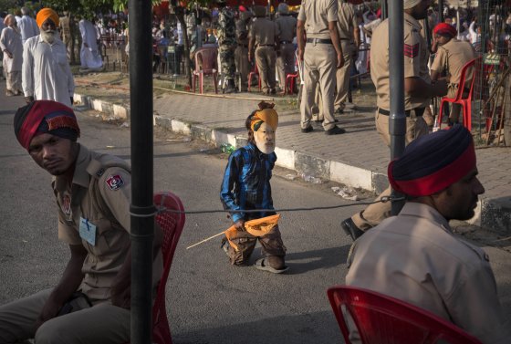 A disabled boy wears a mask of BJP leader Narendra Modi as he walks past a police checkpoint at a rally by Modi on April 25, 2014 in Bathinda, Punjab.
