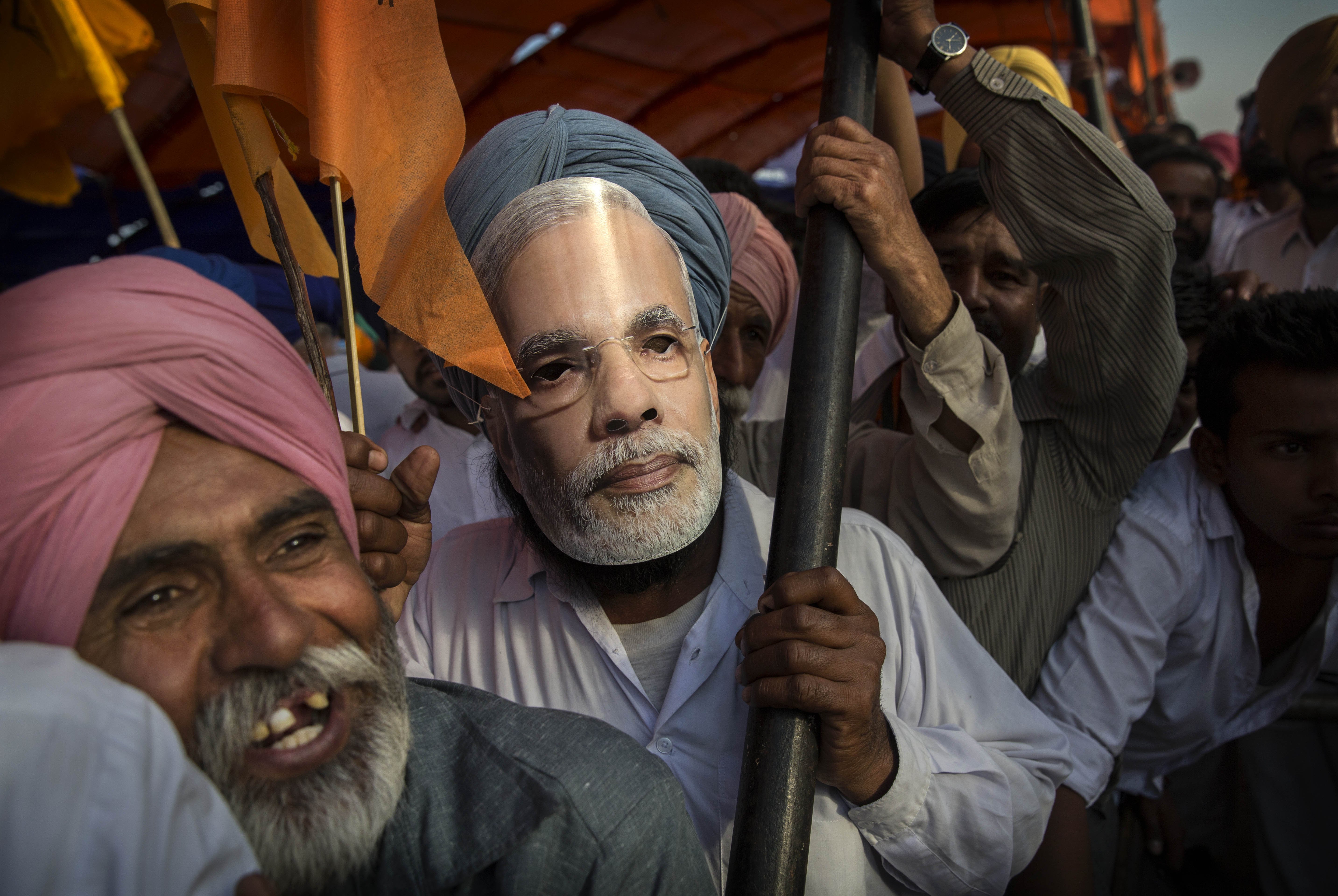 Sikh man wears a mask of BJP leader Narendra Modi as people crowd to hear his speech on April 25, 2014 in Bathinder, Punjab.
