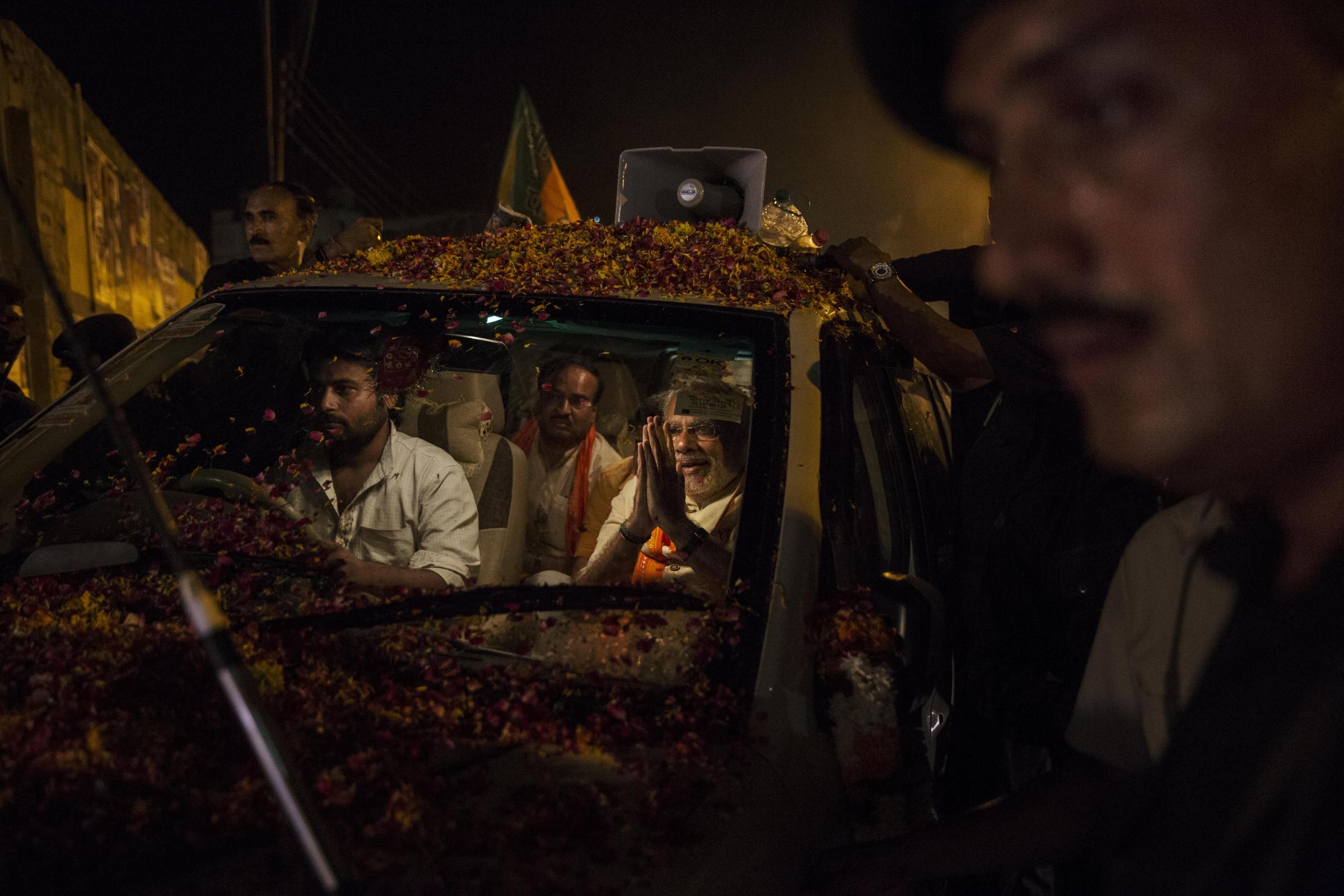 BJP leader Narendra Modi greets supporters as he is surrounded by bodyguards while driving through the streets on May 8, 2014 in Varanasi.