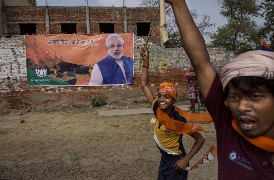 Supporters run passed a banner showing BJP leader Narendra Modi at a rally by the leader on May 8, 2014 in Rohaniya, near Varanasi.