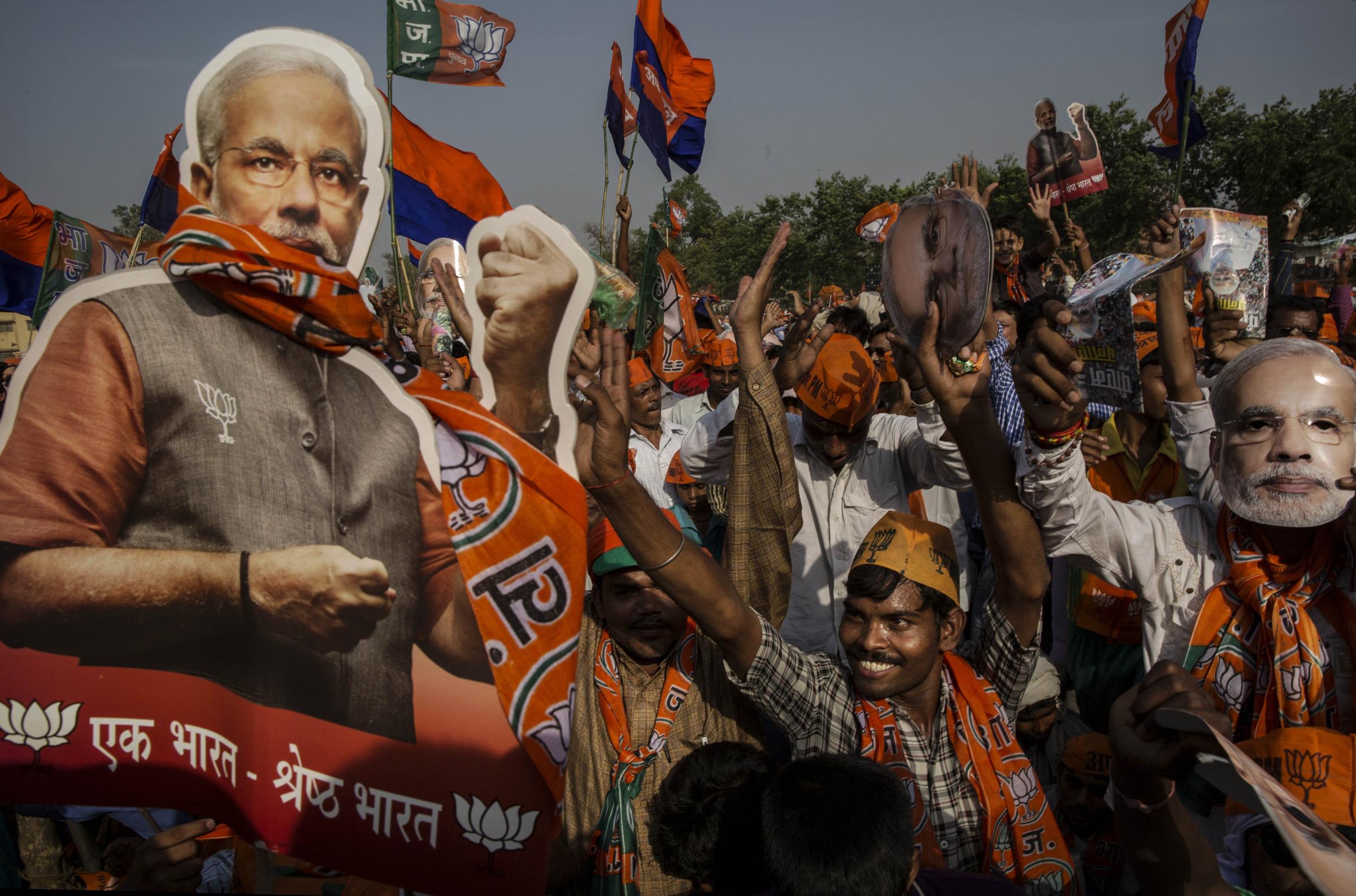 Supporters of BJP leader Narendra Modi cheer during his speech at a rally by the leader on May 8, 2014 in Rohaniya, near Varanasi.