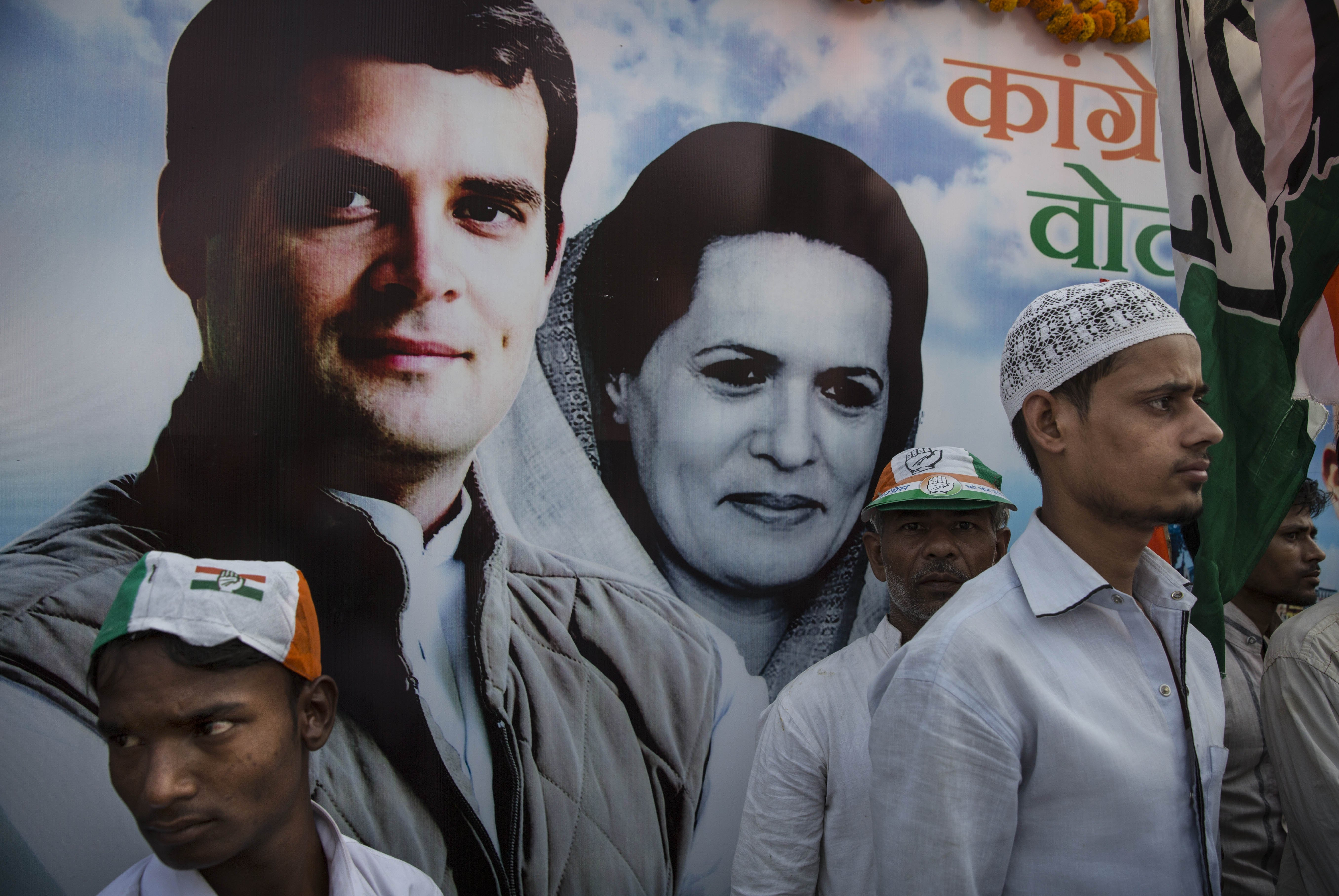Supporters of the Congress Party stand in front of a poster showing Rahul Gandhi and his mother and party president Sonia Gandhi as they wait before a rally on May 10, 2014 in  Varanasi.