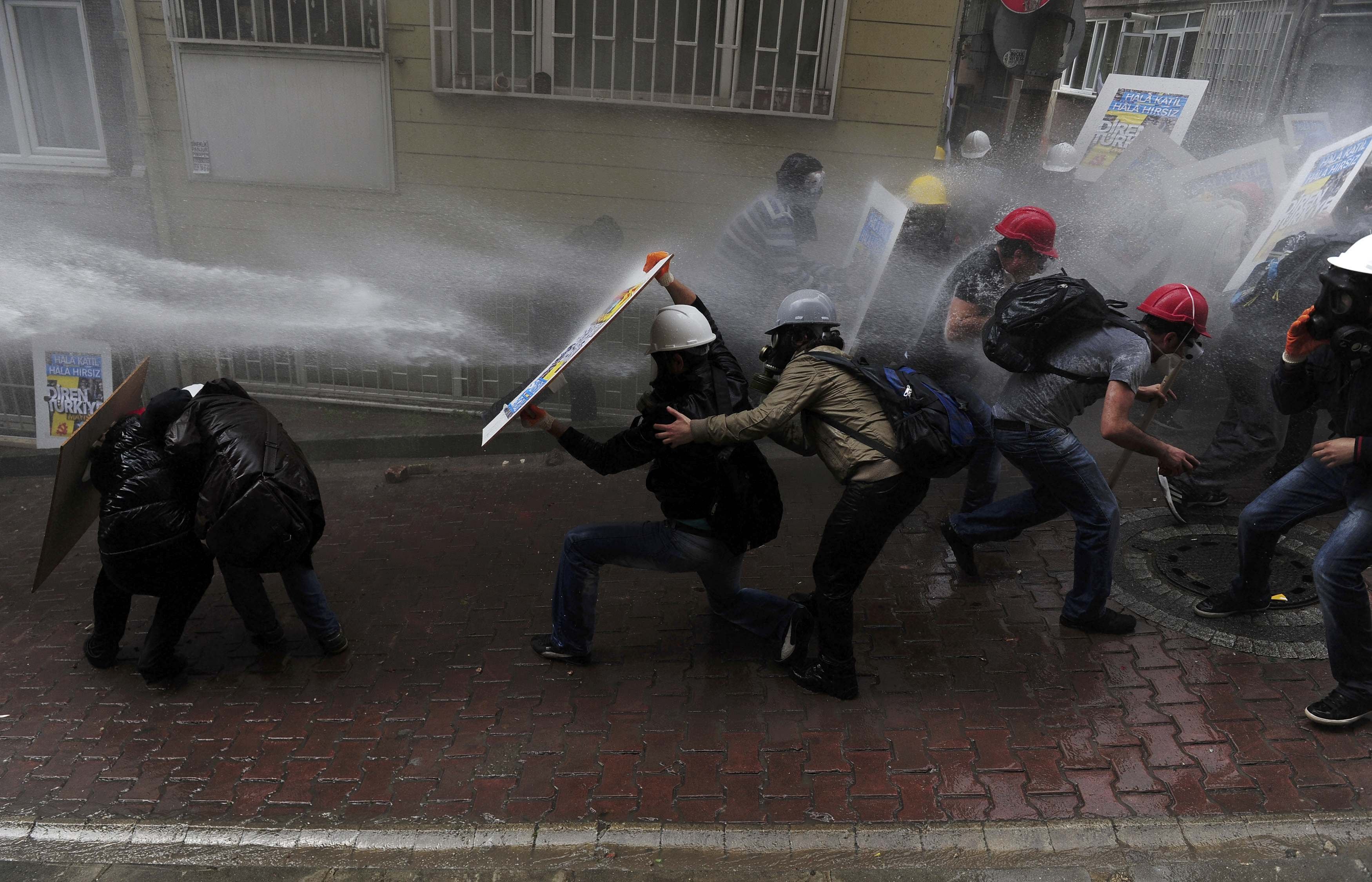 Protesters shield themselves as riot police use water cannon to disperse them during a May Day demonstration in Istanbul May 1, 2014.