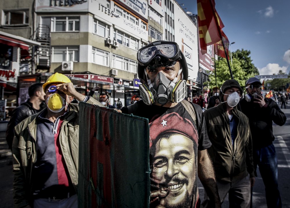 A Turkish protester wearing a gas mask and a hard hat takes cover during clashes with riot police who tried to prevent demonstrators from reaching Taksim Square in Istanbul for a May Day rally on May 1, 2014.