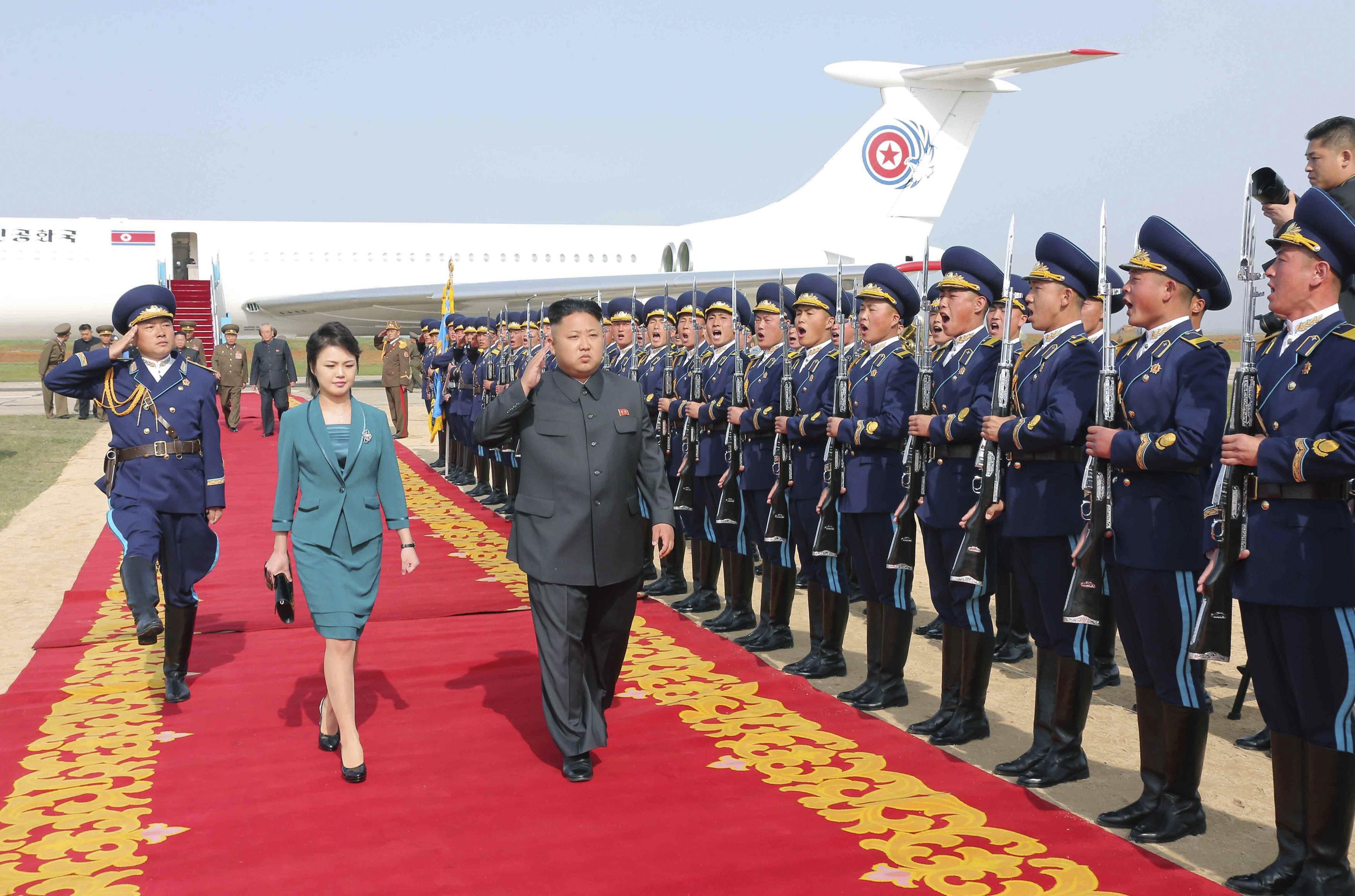 North Korean leader Kim Jong Un salutes as he and his wife Ri Sol Ju walk past the guard of honour upon arriving for the 2014 Combat Flight Contest of the Korean People's Air Force in Pyongyang, in a photo released on May 10, 2014.