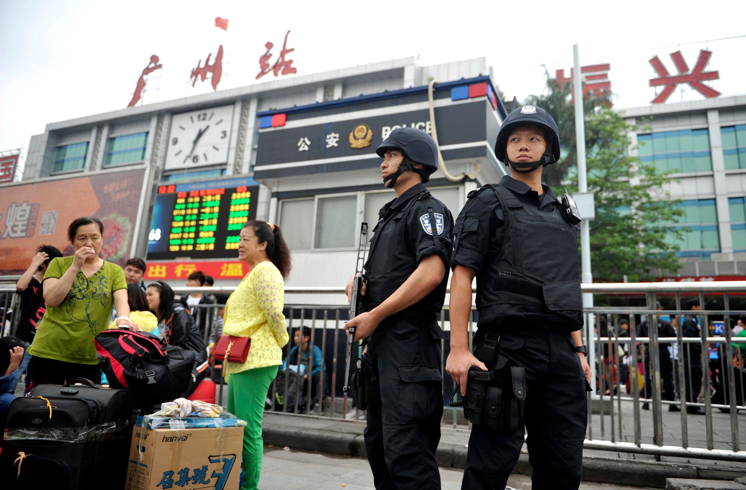Armed policemen stand guard next to passengers after a knife attack at a railway station in Guangzhou, Guangdong province May 6, 2014.