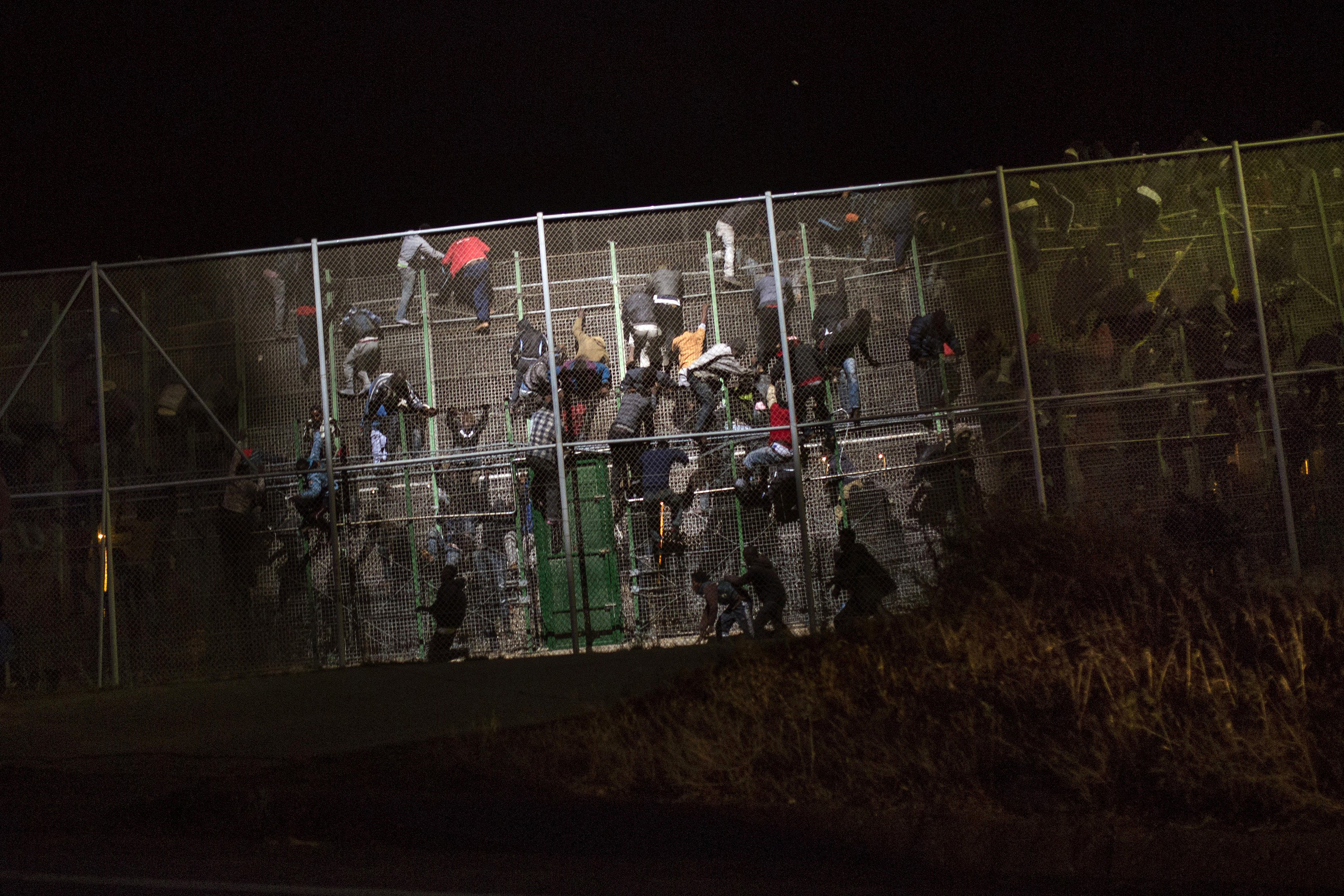 Sub-Saharan migrants scale a metallic fence that divides Morocco and the Spanish enclave of Melilla, early on May 28,  2014. (Santi Palacios—AP)