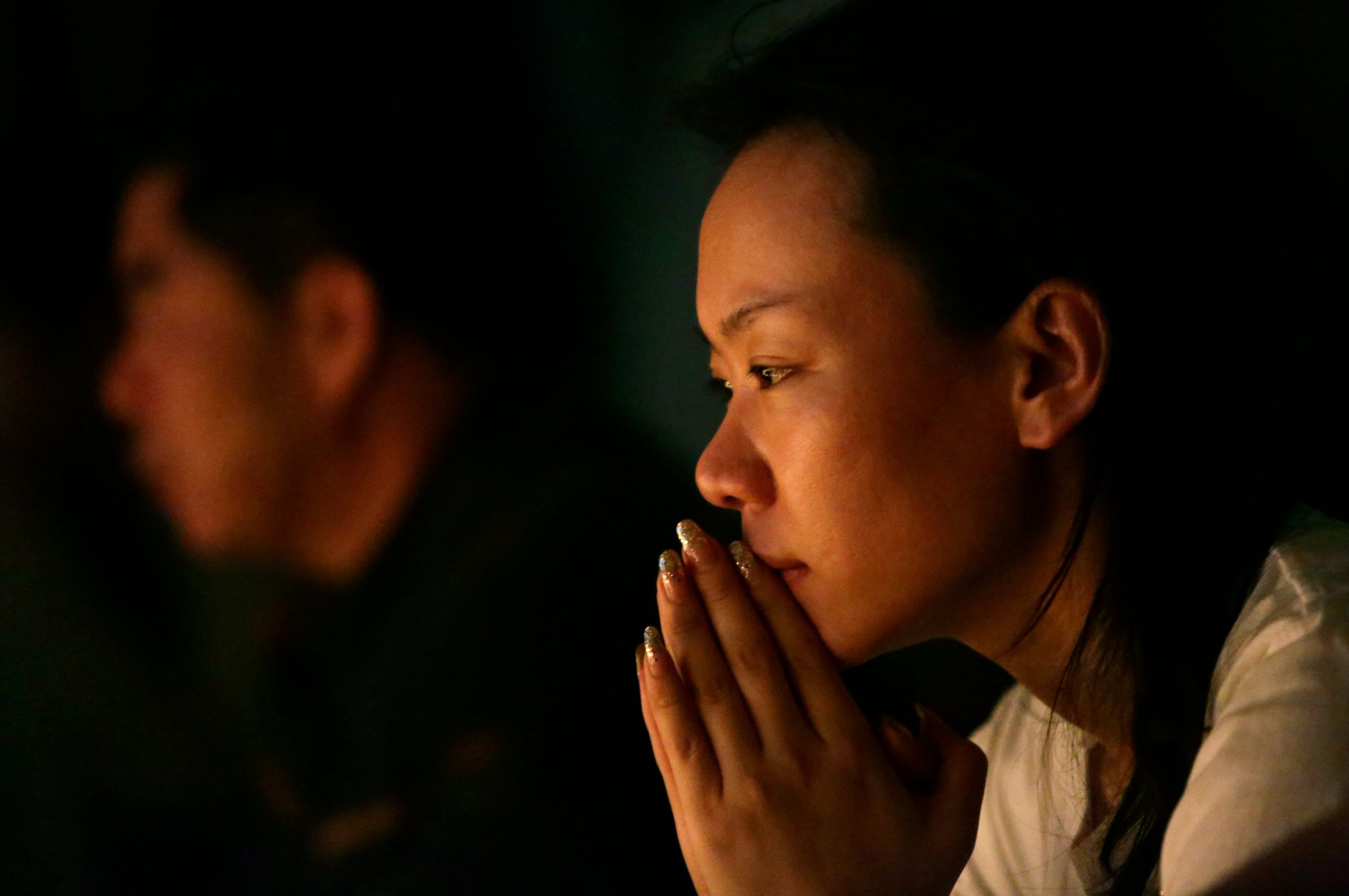 Family members pray during a candlelight vigil for passengers onboard the missing Malaysia Airlines Flight MH370 in the early morning, at Lido Hotel, in Beijing on April 8, 2014.