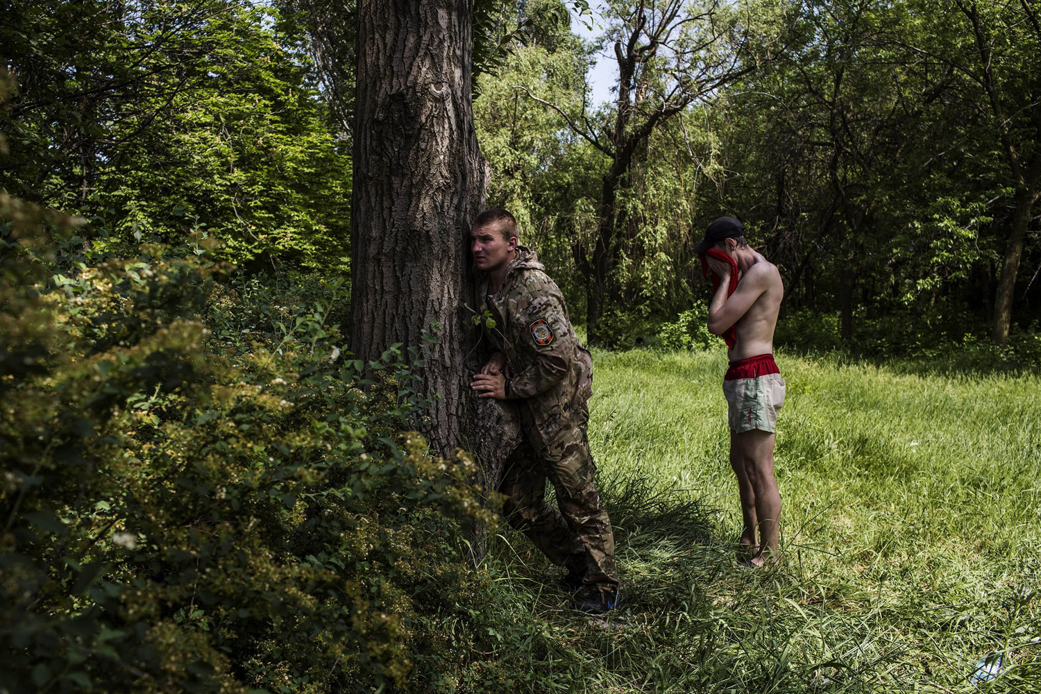 May 26, 2014. A pro-Russian fighter (L) takes position behind a tree during clashes against Ukrainian forces near the airport in Donetsk.