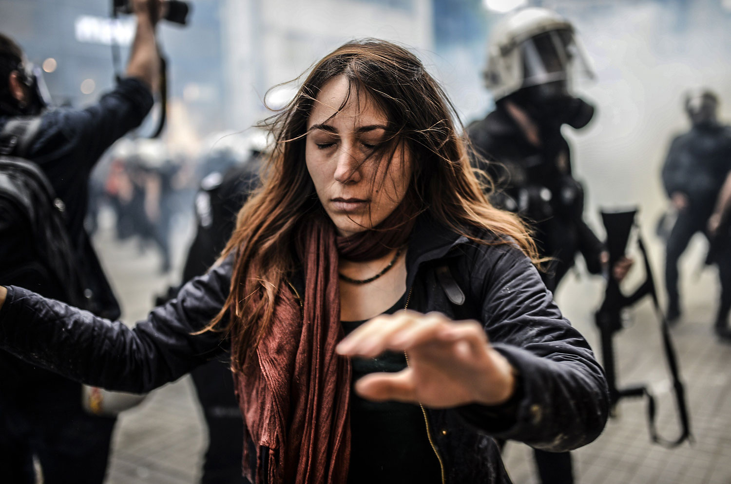 A protester walks away with closed eyes as Turkish riot police officers fire tear gas to disperse demonstrators.