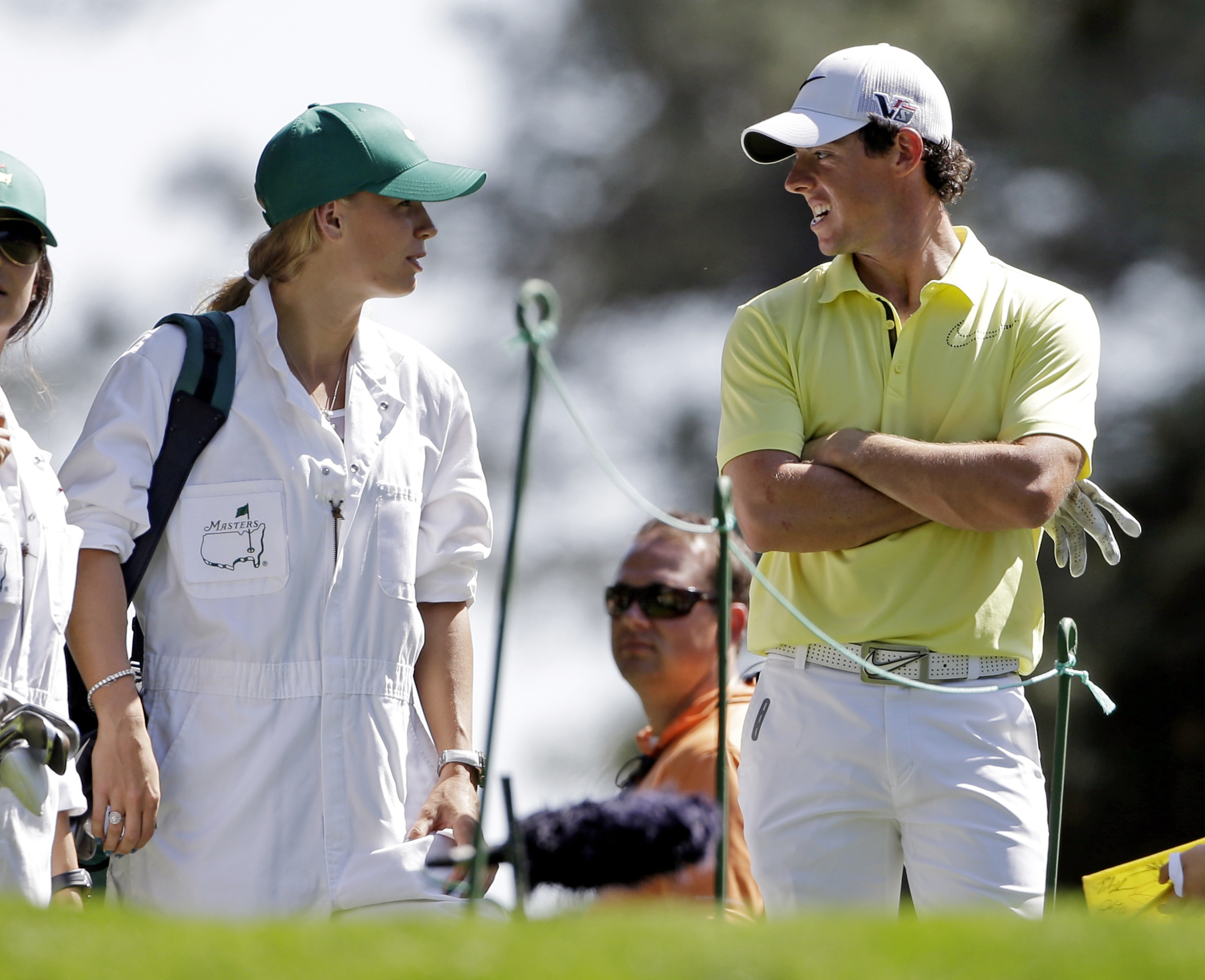 Rory McIlroy, of Northern Ireland, speaks with tennis player Caroline Wozniacki who caddied for him during the par three competition before the Masters golf tournament in Augusta, Ga. on April 10, 2013. (Darron Cummings—AP)