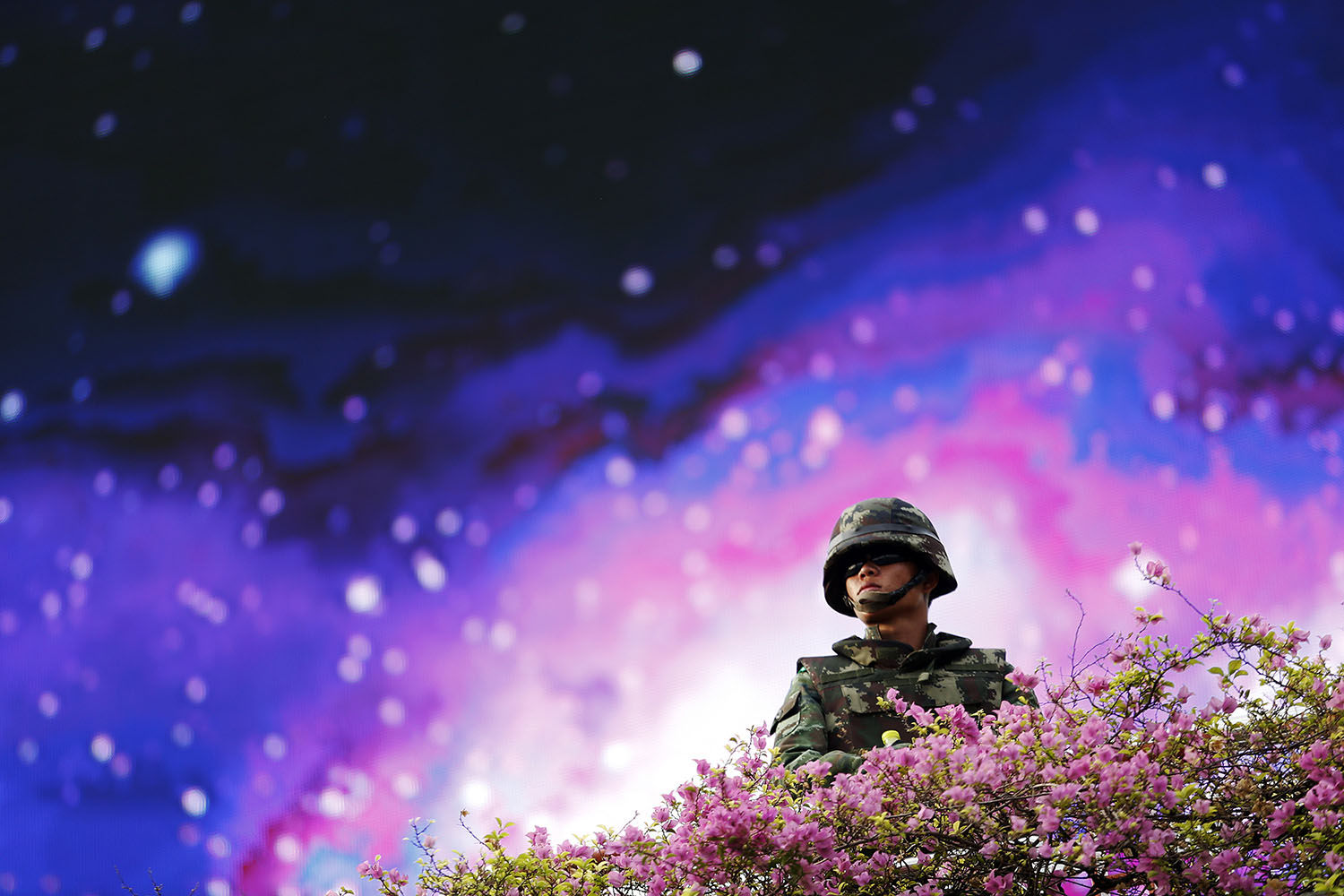 A soldier takes up position in front of a large screen at the Victory Monument in Bangkok