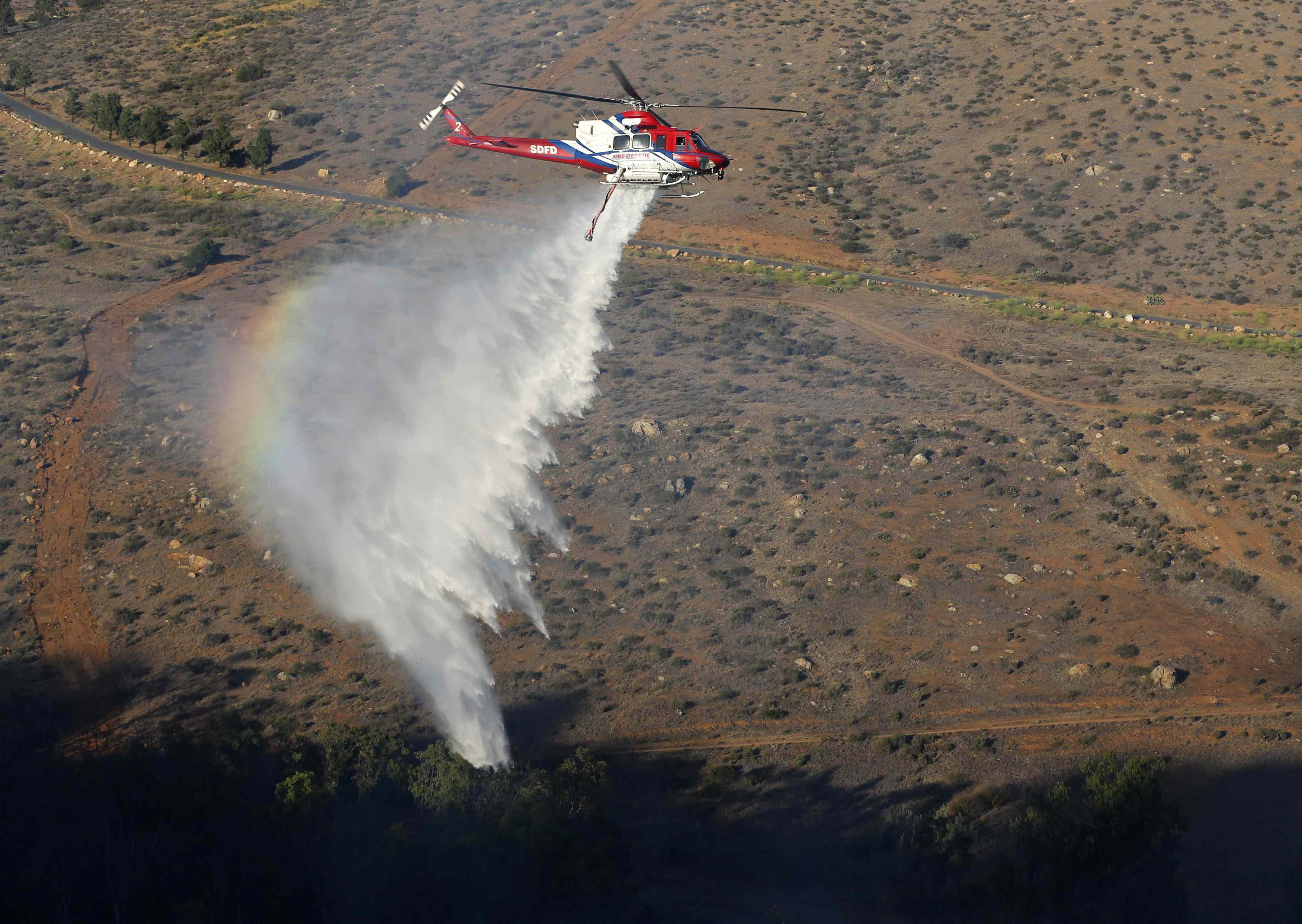 A helicopter drops water to extinguish fire and protect homes north of San Diego on May 13, 2014.