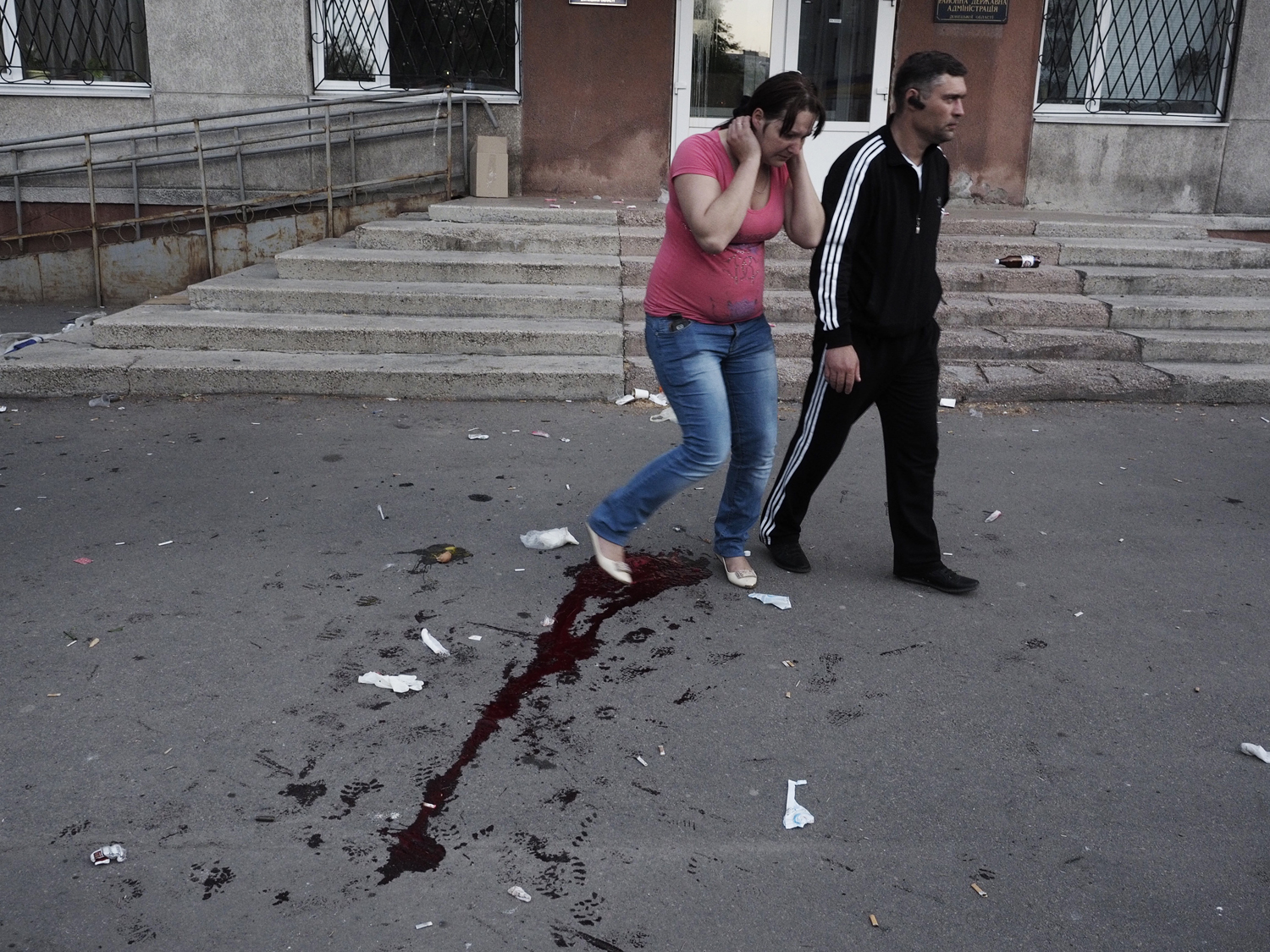 May 11, 2014. A man and woman walk through the blood trail left after a man was shot by an armed guard.
