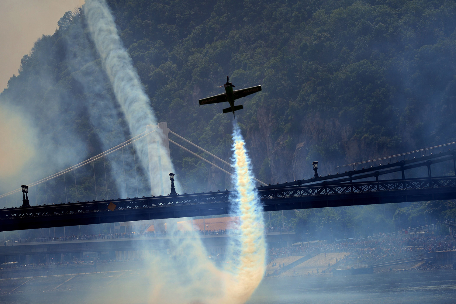 Hungarian pilot and European champion Zoltan Veres flies under the oldest Hungarian bridge, the 'Lanchid' (Chain Bridge) with his 'MXS' type plane on May 1, 2014 during a Red Bull flying and car show around the Danube River of Budapest downtown.