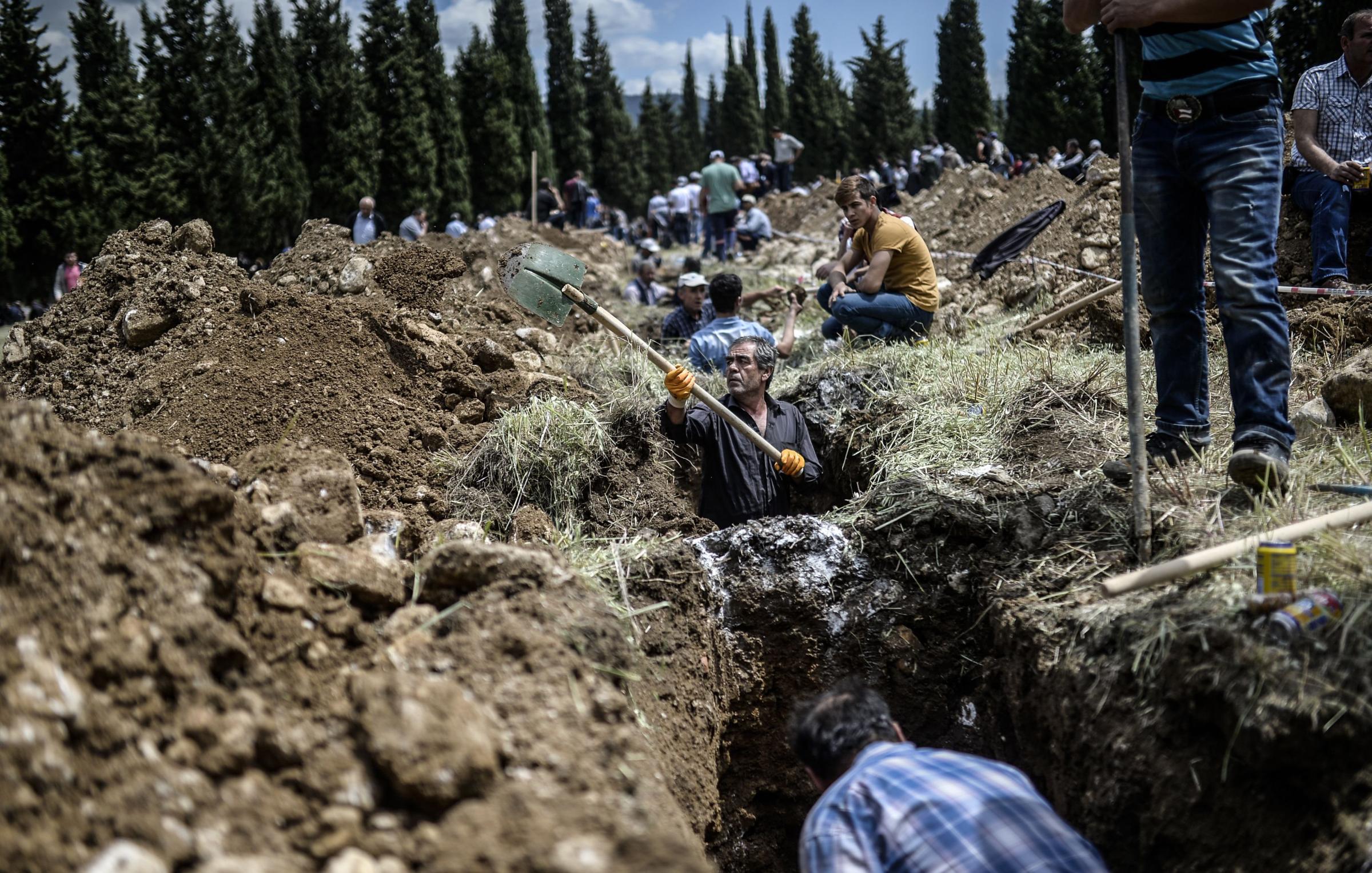 People dig graves for miners in a cemetery during the funeral ceremony of miners who died in an explosion on May 15, 2014, in the western town of Soma in the Manisa province.