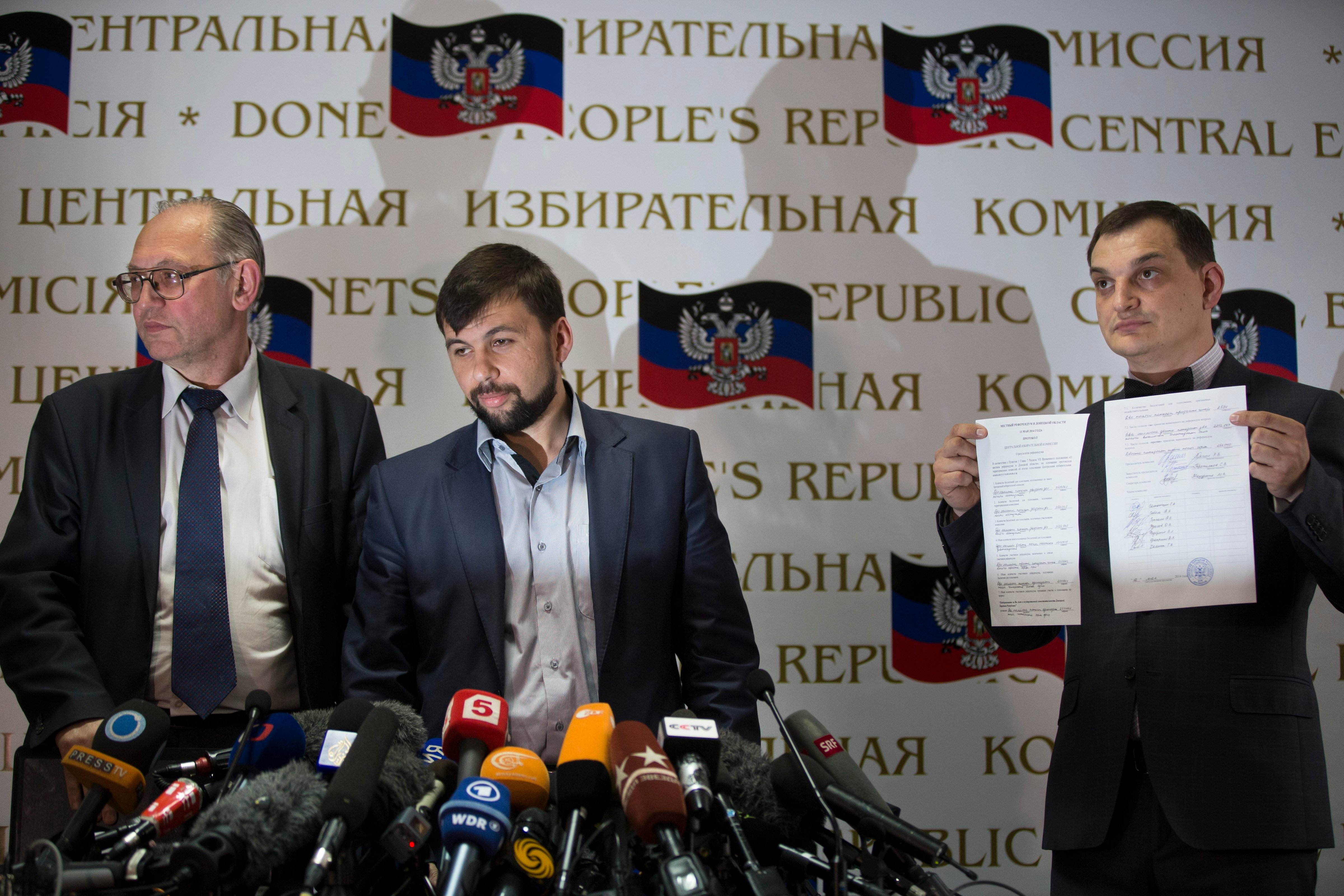 Co-chairman of the Presidium of the People's Republic of Donetsk Boris Litvinov, left, Insurgent leader head of the elections commission of the so-called Donetsk People's Republic Denis Pushilin, and vote-counter Roman Lyagin, right, show documents with the results of Sunday's referendum at a news conference in Donetsk, May 12, 2014. (Alexander Zemlianichenko—AP)