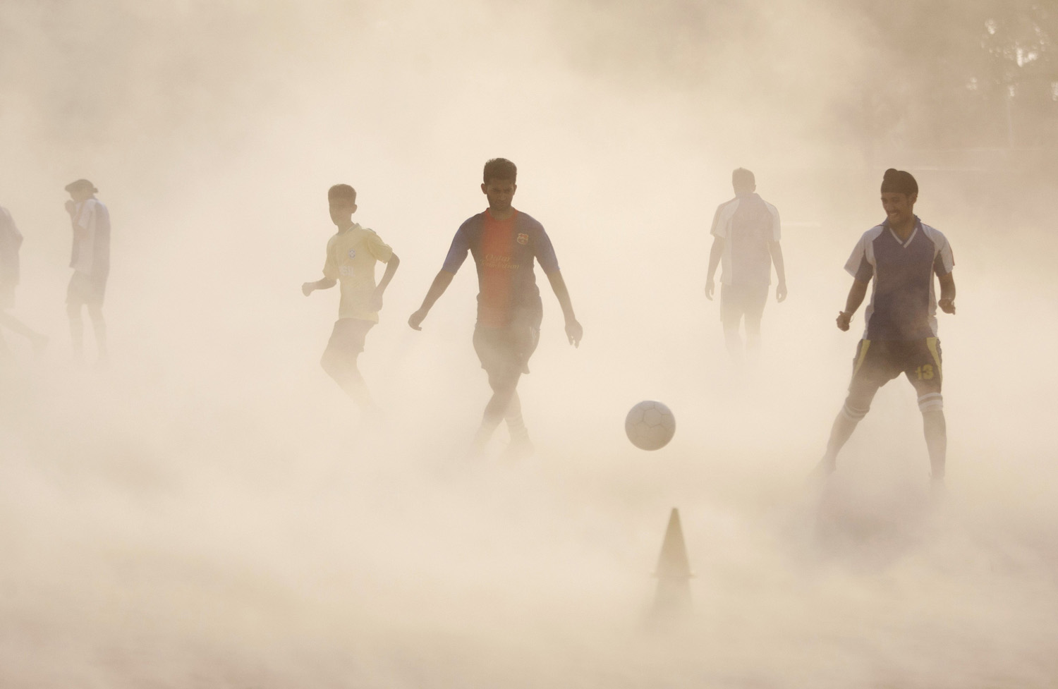Aspiring young Indian soccer players continue with their practice during a dust storm in Jammu, India on June 11, 2014.