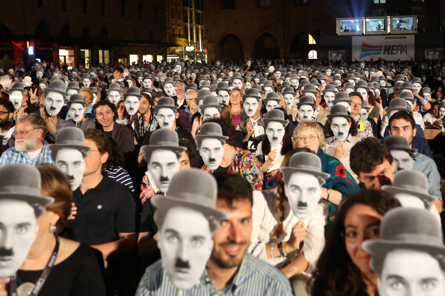 Members of the audience hold up face masks of the character 'The Little Tramp' (aka Charlot) on the occasion of the official celebrations for the centenary of the birth of British-born actor and filmmaker Charlie Chaplin during an outdoor live orchestral screening at Piazza Maggiore in Bologna, Italy, June 25, 2014.