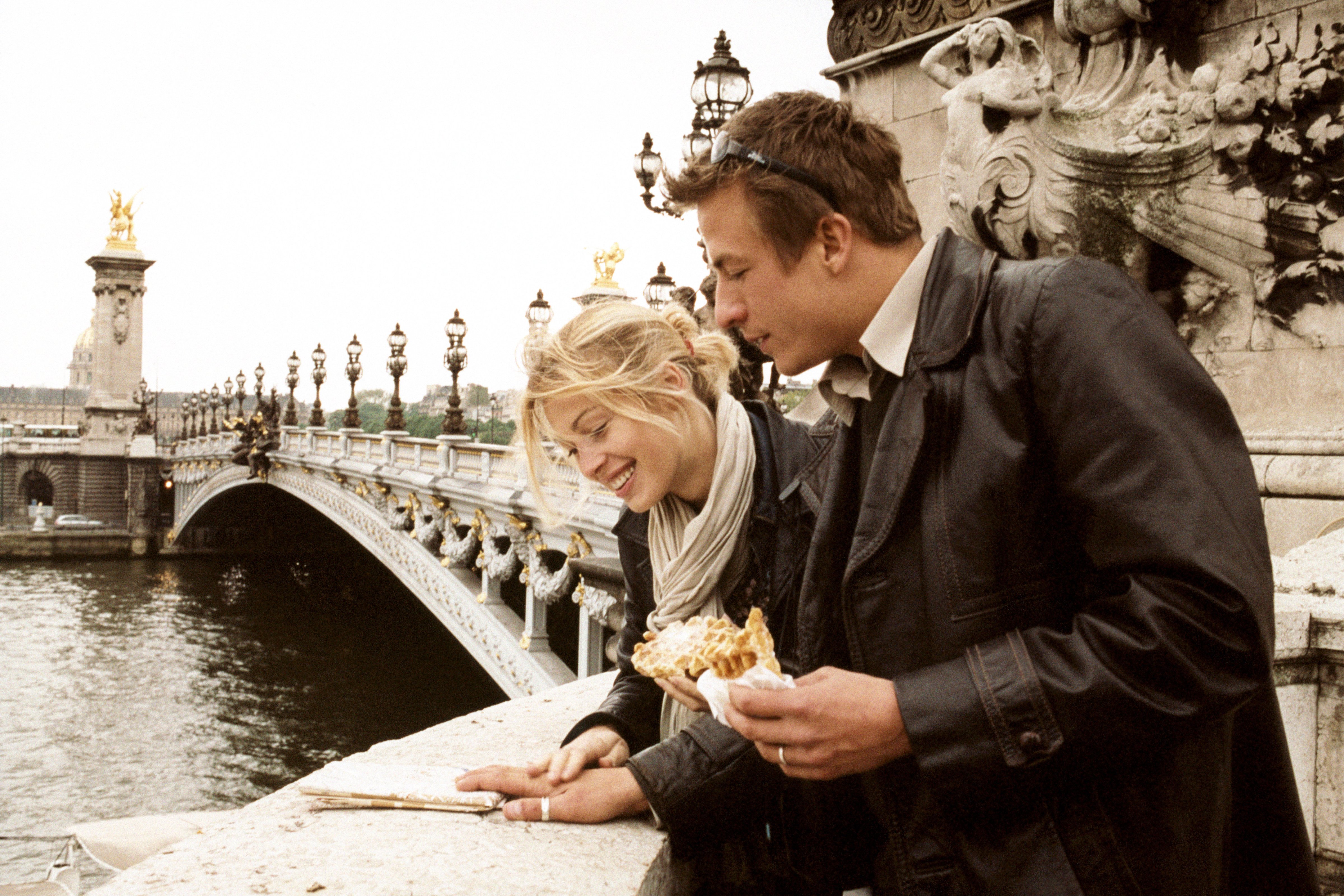 Young couple looking at map on Alexandre III bridge in Paris, France. (Jean Luc Morales—Getty Images)