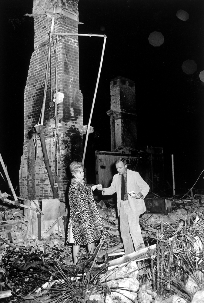 LIFE magazine editor Richard Stolley helps Zsa Zsa Gabor through the remains of her Bel Air, Calif., home, destroyed by fire in November 1961.