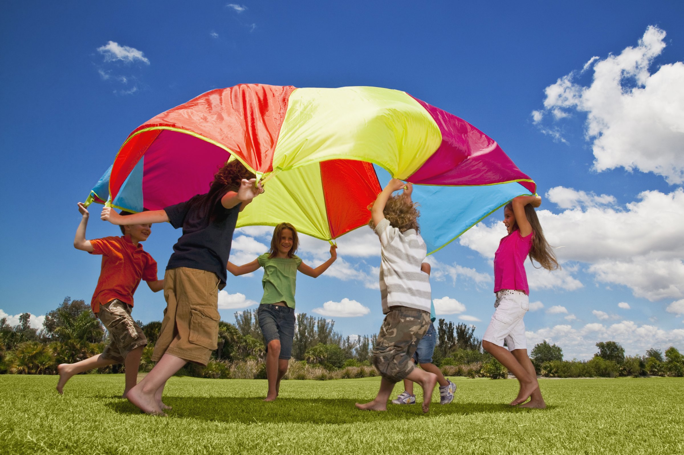 Group of kids playing with a parachute in the park
