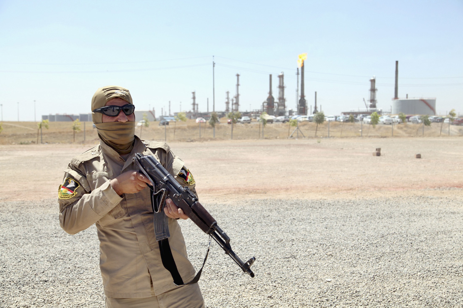 A member of Kurdish security forces takes up position with his weapon as he guards an oil refinery on the outskirts of Mosul