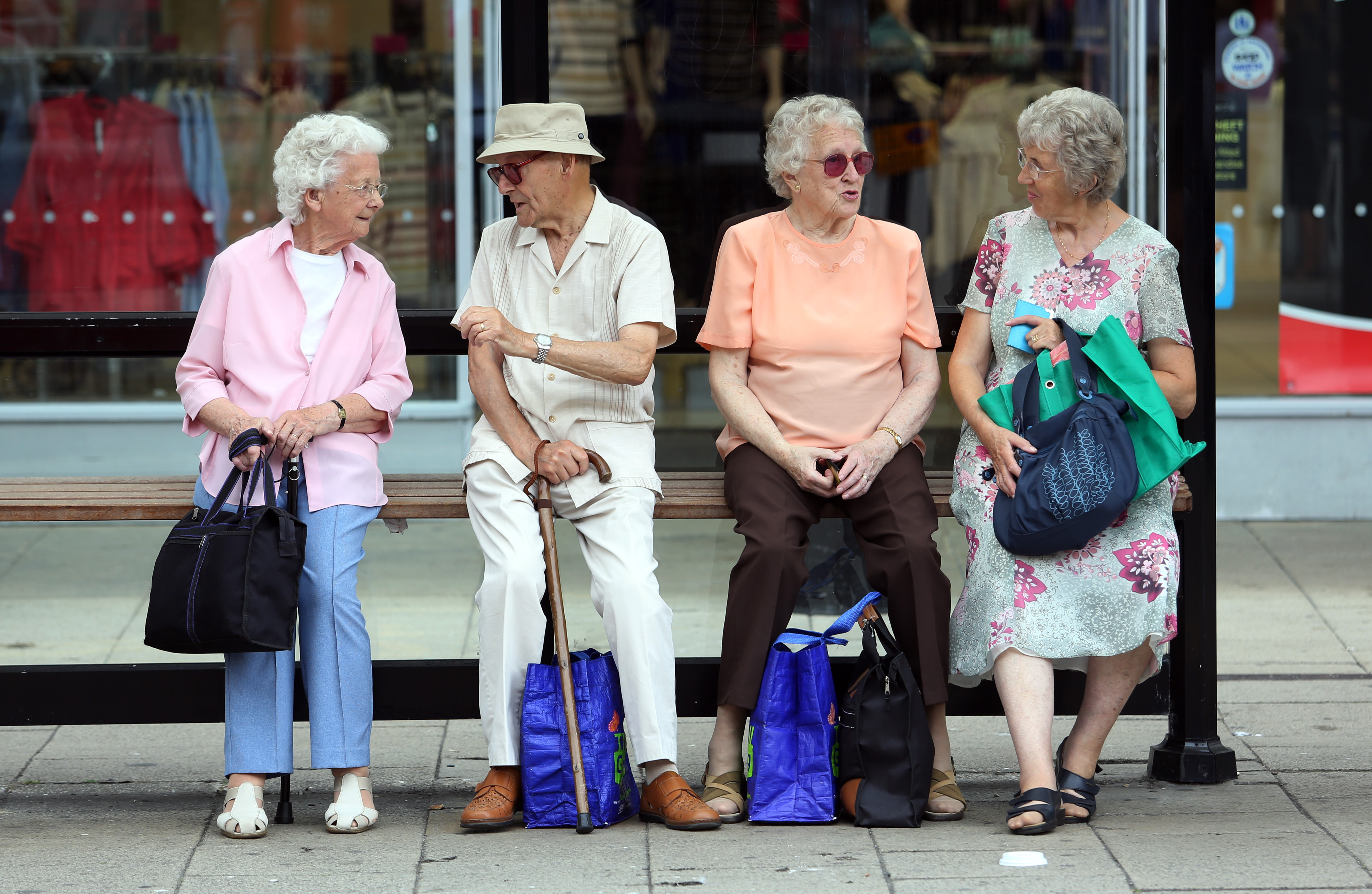 Elderly people sit with their shopping bags as they wait for transportation at a bus stop in Hastings, U.K., on Tuesday, July 23, 2013. (Chris Ratcliffe—Bloomberg/Getty Images)