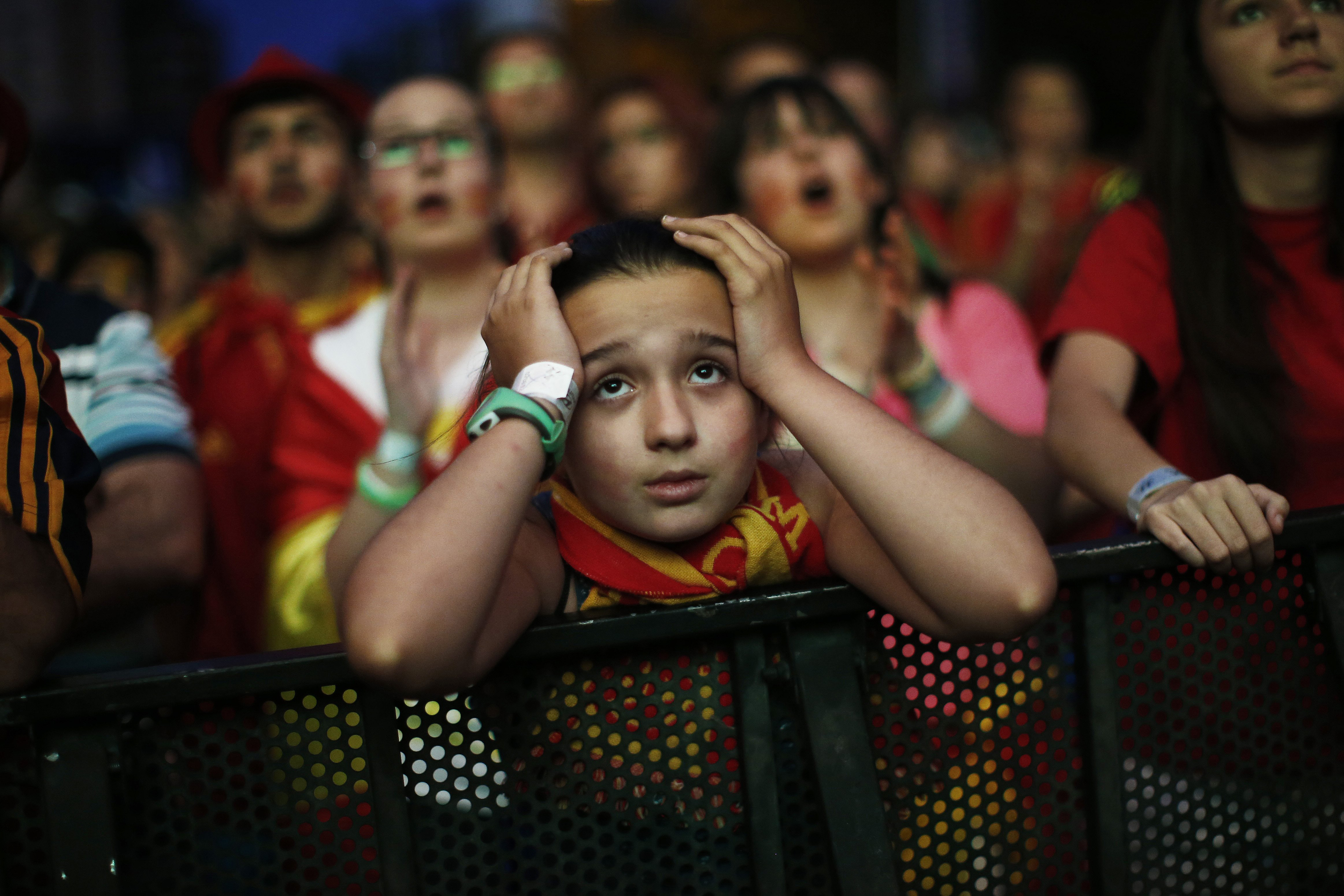 A Spanish fan holds her head as she watches, on a giant display, the match between Spain and Chile, in Madrid on June 18, 2014.