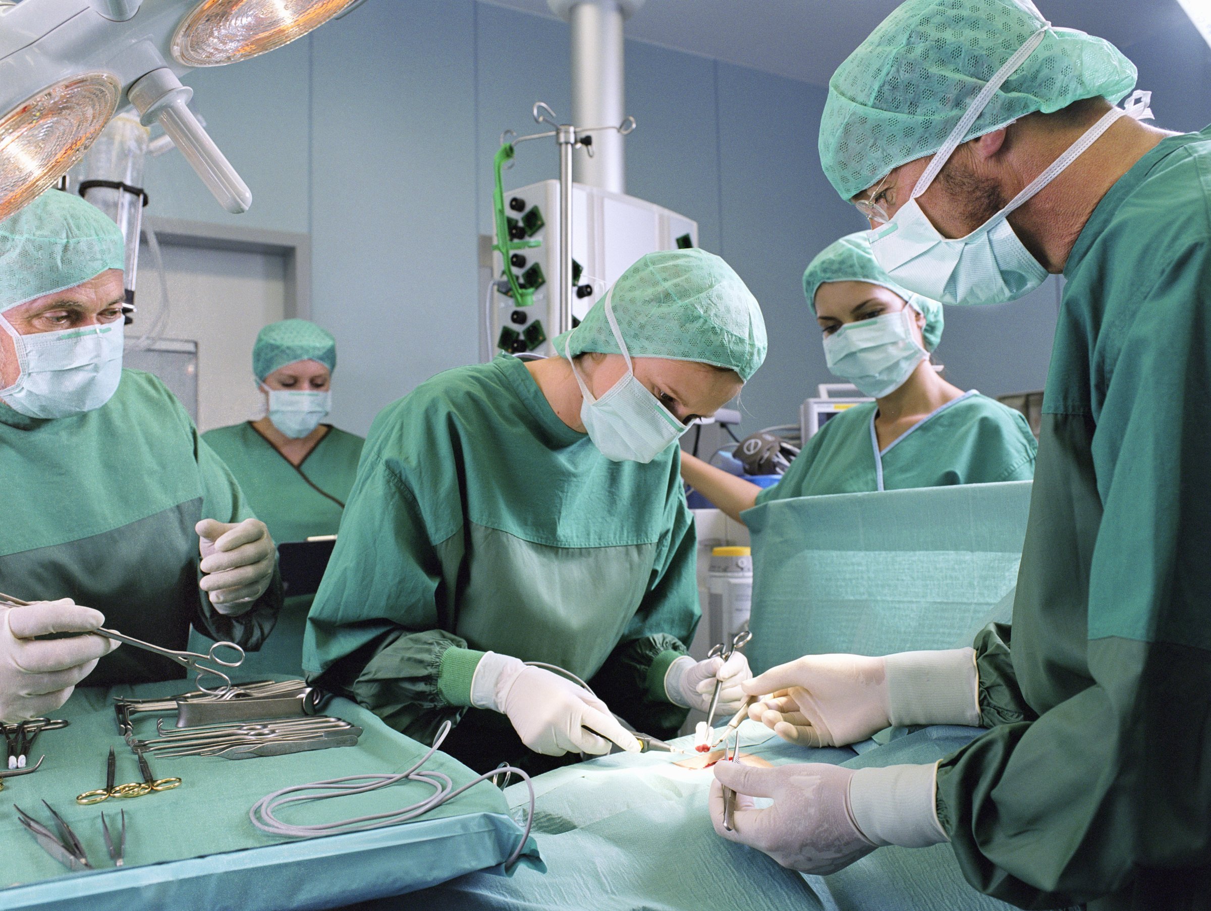 A group of surgeons work in an operating theatre.