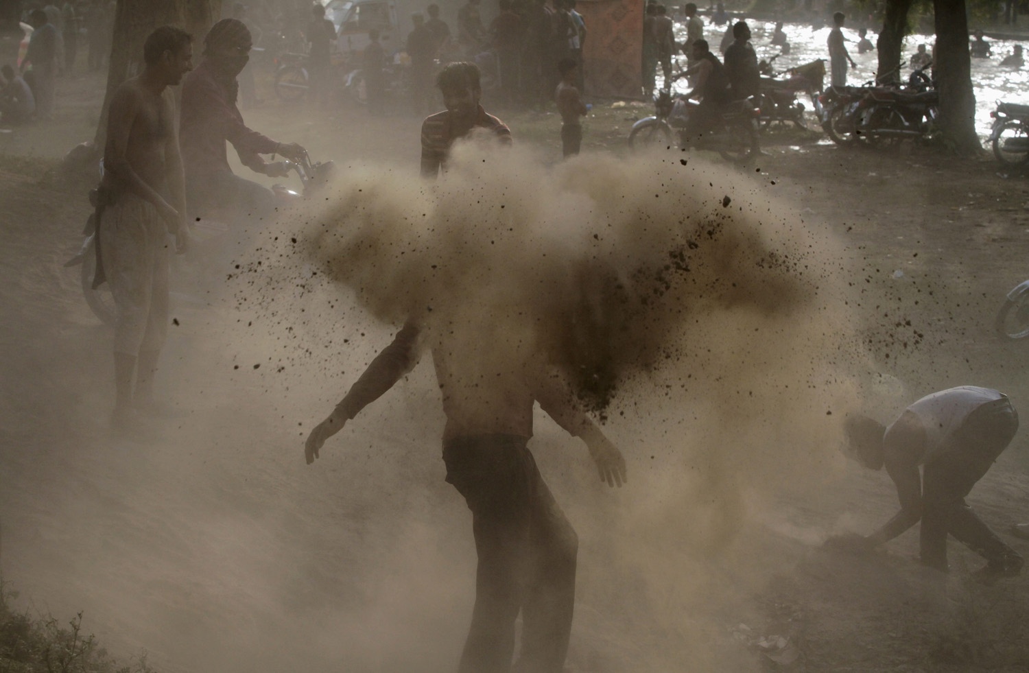 Locals play with dirt before a dip to cool off in a nearby canal on a hot day in Lahore, Pakistan on  June 8, 2014.