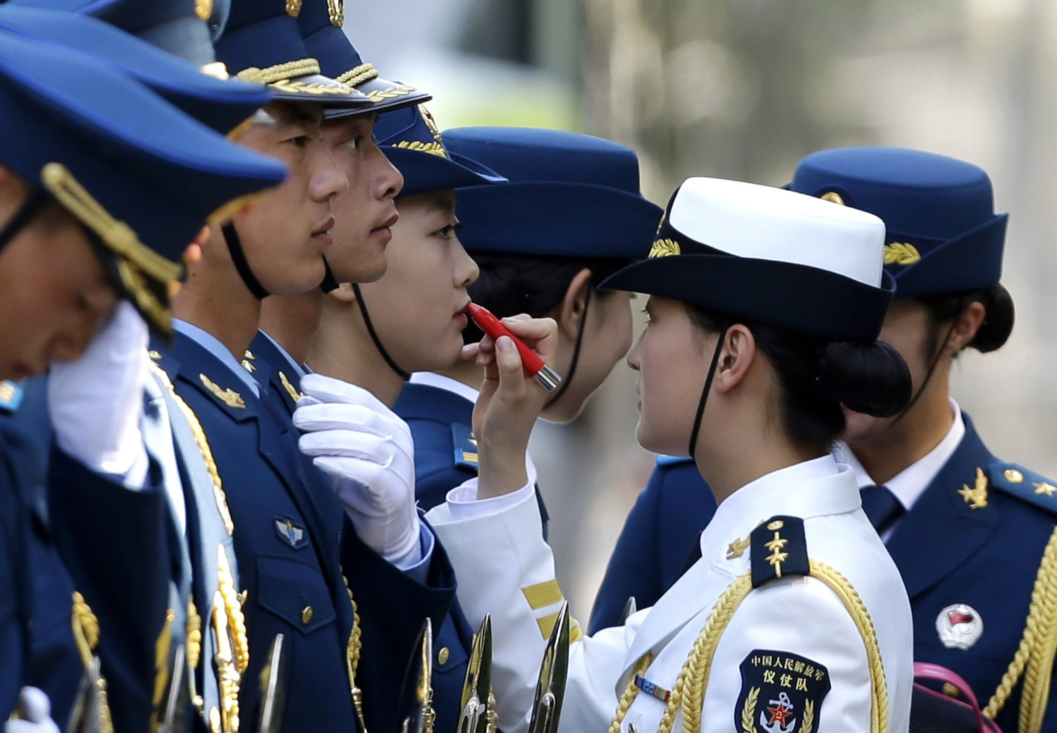 A female honour guard has lipstick applied as they prepare for an official welcoming ceremony for Italy's Prime Minister Matteo Renzi outside the Great Hall of the People in Beijing, June 11, 2014.
