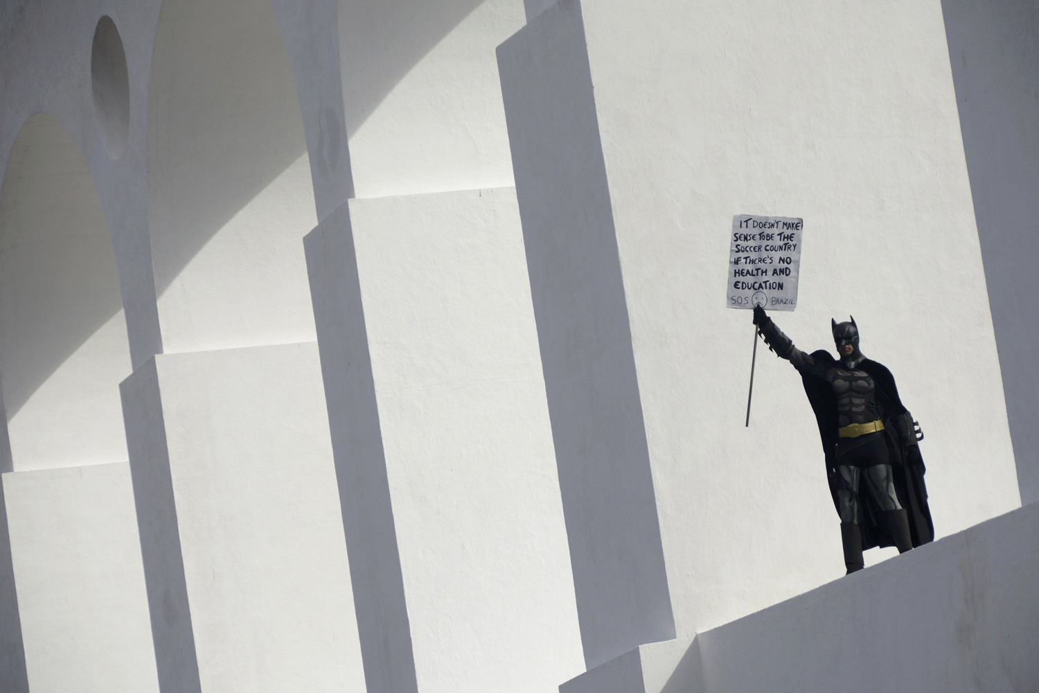 An anti-government demonstrator dressed as Batman holds a sign on the Lapa Arches during a protest against the 2014 World Cup in Rio de Janeiro