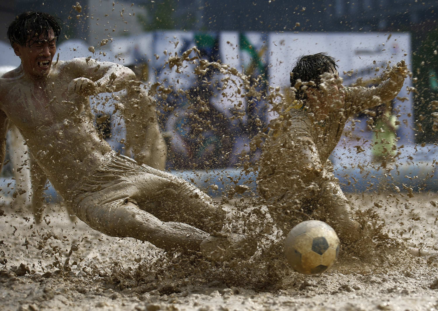 Players battle for the ball during their match at the swamp soccer China tournament in Beijing, June 26, 2014.