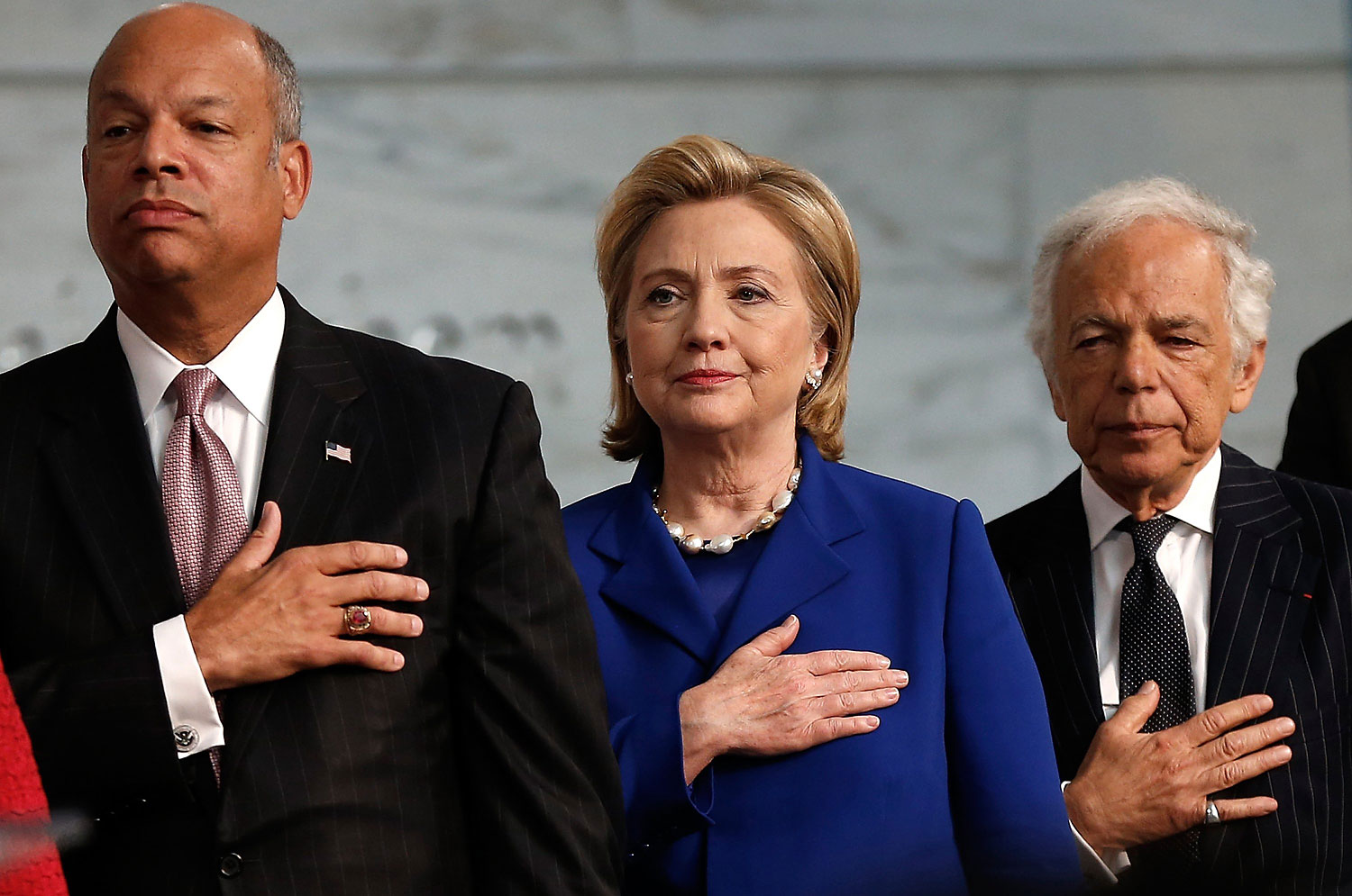 From left, U.S. Secretary of Homeland Security Jeh Johnson, Former U.S. Secretary of State Hillary Clinton and designer Ralph Lauren say the Pledge of Allegiance during a naturalization ceremony at the National Museum of American History June 17, 2014 in Washington, DC. (Win McNamee—Getty Images)
