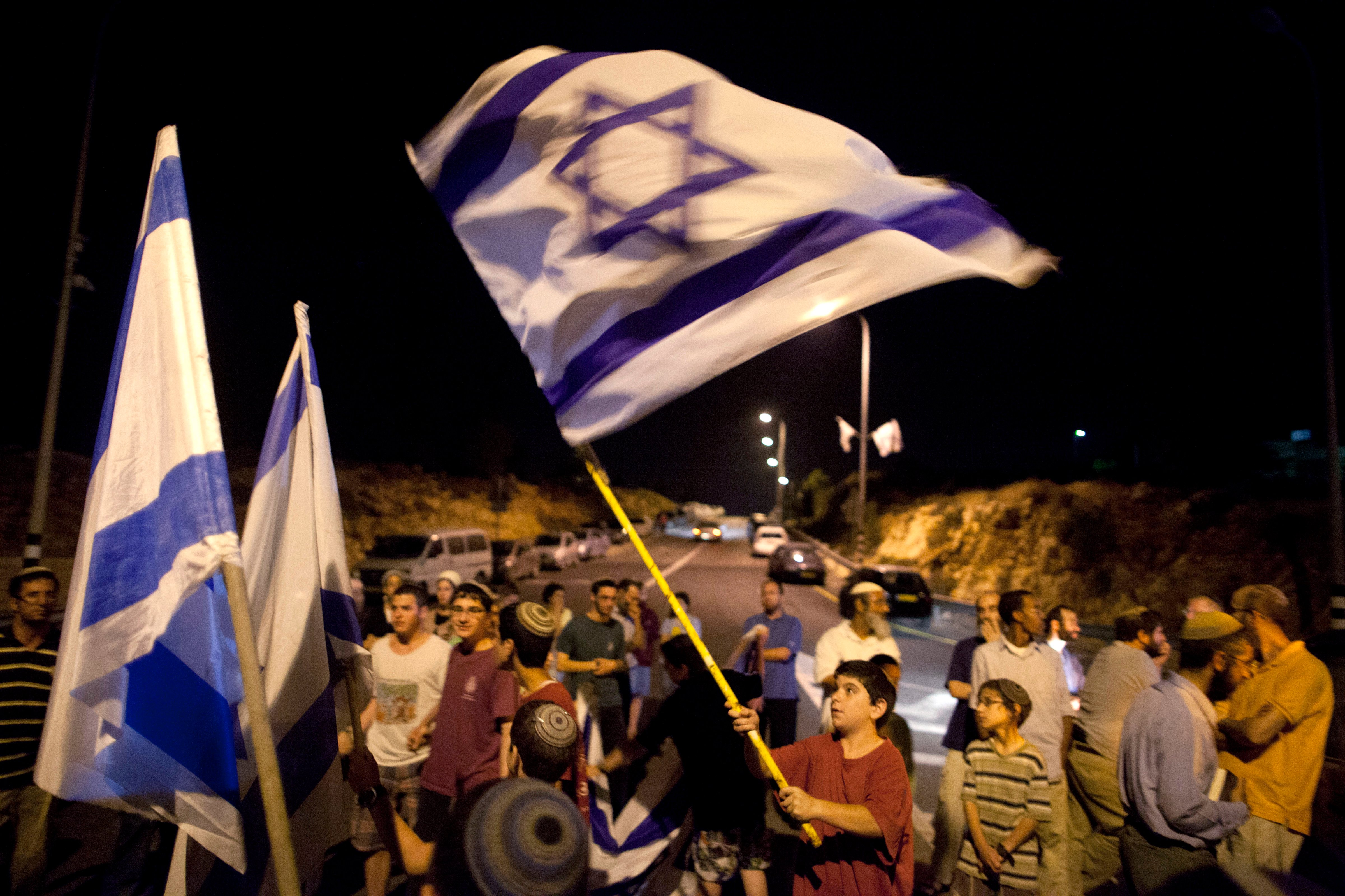 Israeli settlers hold flags on June 30, 2014, at the entrance to Halhoul, north of Hebron, West Bank (Lior Mizrahi—Getty Images)