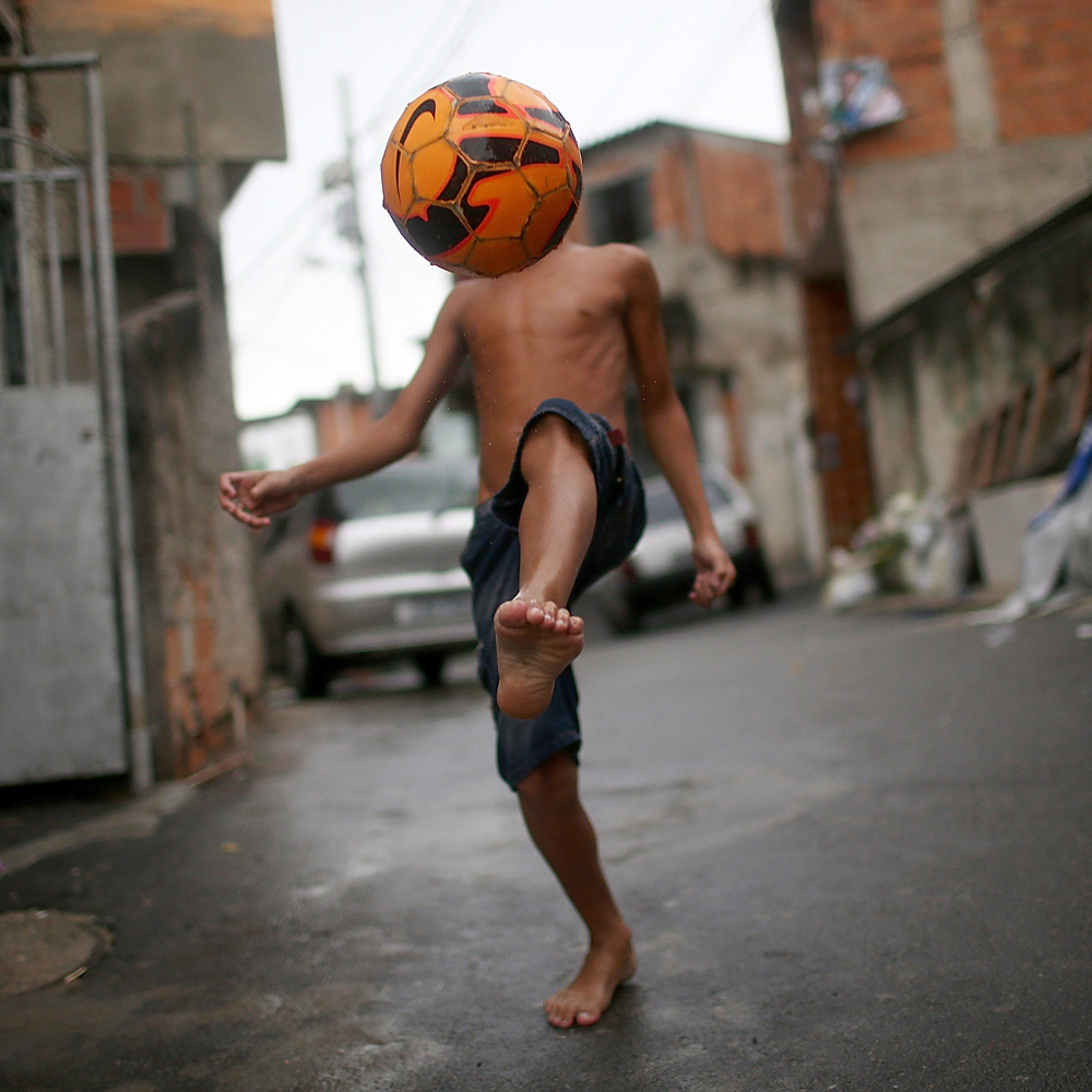 Mar. 23, 2014. A boy shows off his soccer skills in the Complexo do Alemao pacified 'favela' community on in Rio de Janeiro, Brazil. The 'favela' was previously controlled by drug traffickers and is now occupied by the city's Police Pacification Unit (UPP). A number of UPP's were attacked by drug gang members on March 20 and some pacified favelas will soon receive federal forces as reinforcements. The UPP are patrolling some of Rio's favelas amid the city's efforts to improve security ahead of the 2014 FIFA World Cup and 2016 Olympic Games.