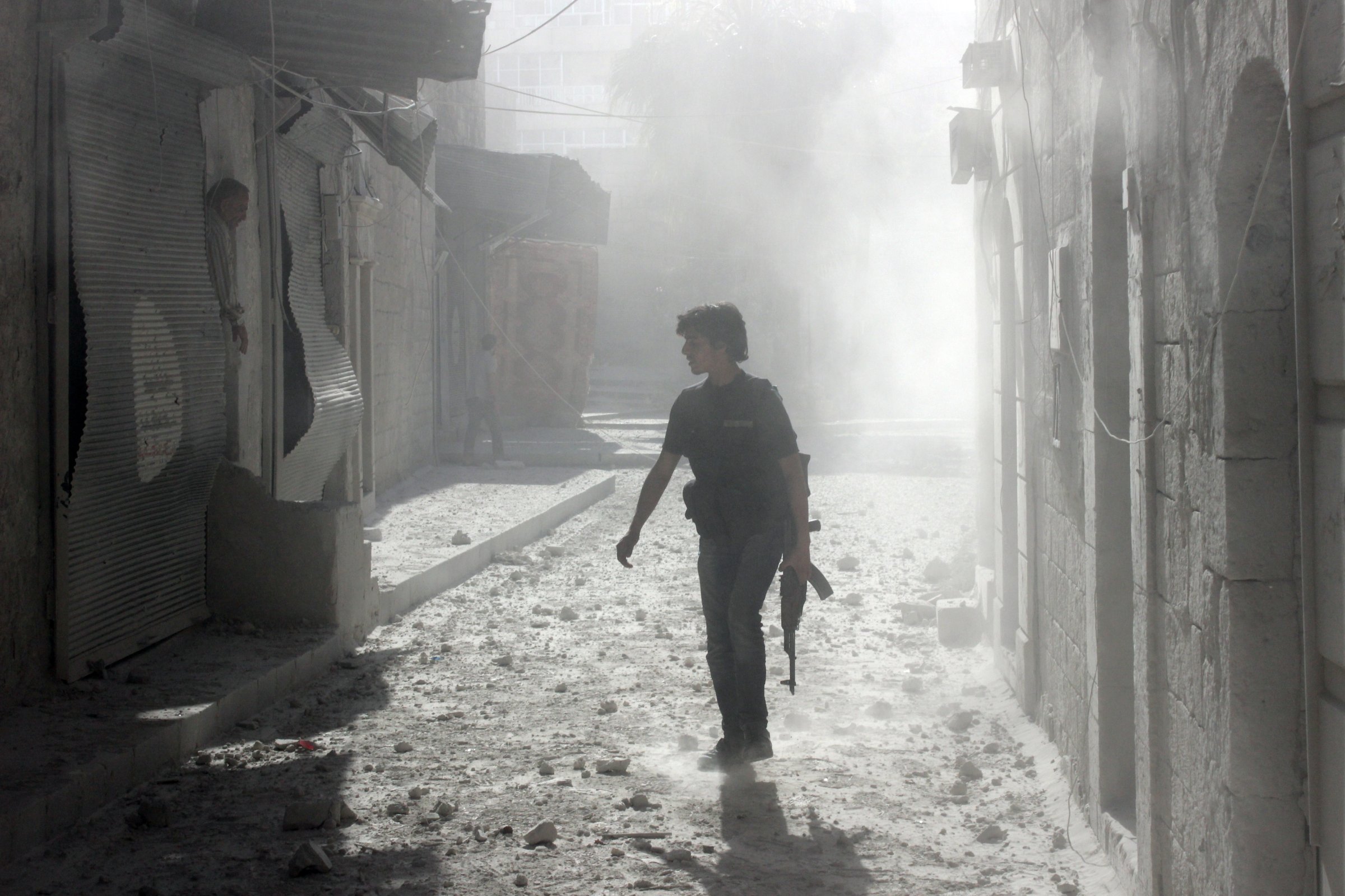 A rebel fighter walks on a street in the Syrian city of Aleppo following a reported bombardment with explosive-packed "barrel bombs" by the government forces on April 27, 2014