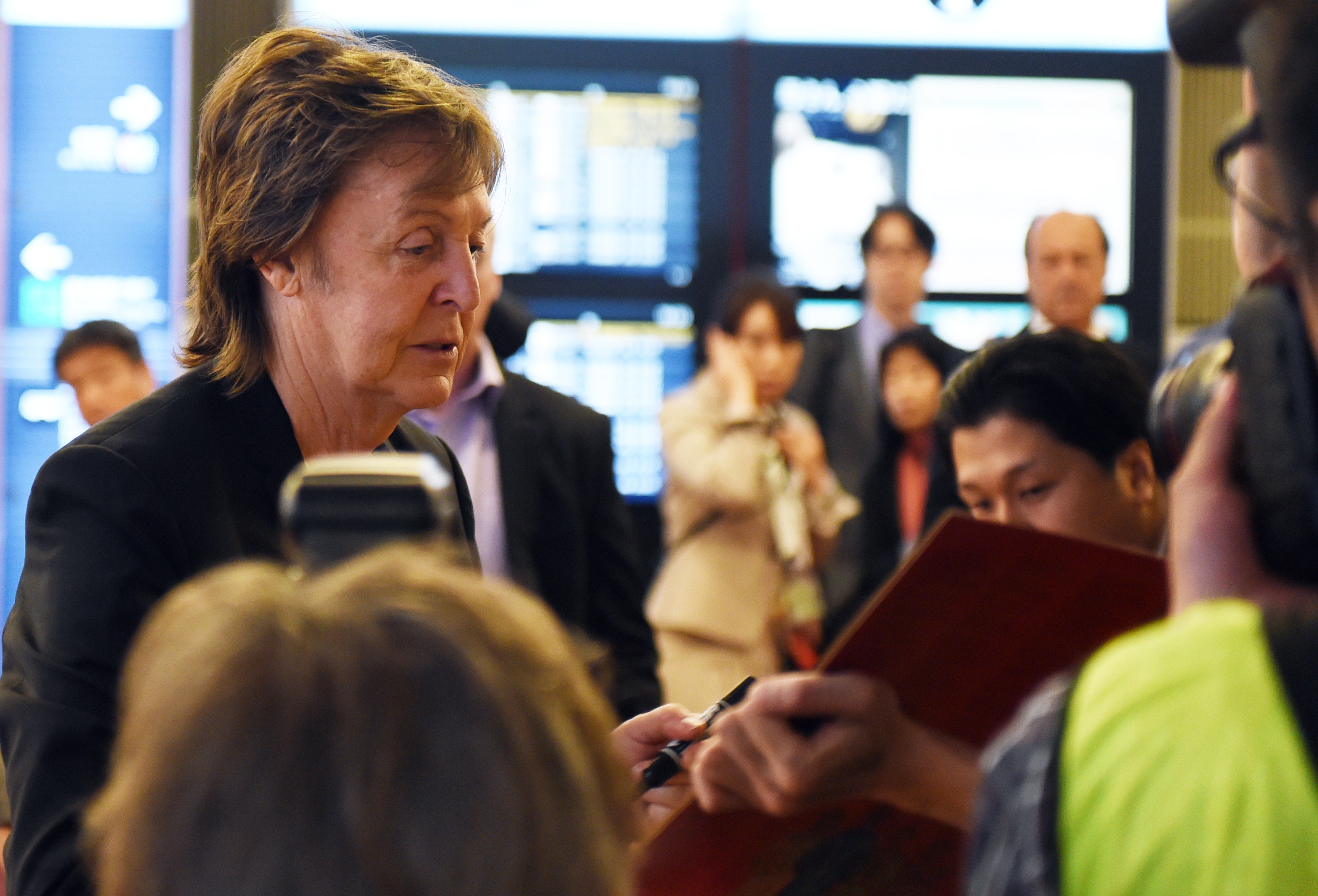Paul McCartney (L) signs his autograph upon his arrival at the Haneda airport in Tokyo on May 15, 2014. (TOSHIFUMI KITAMURA—AFP/Getty Images)