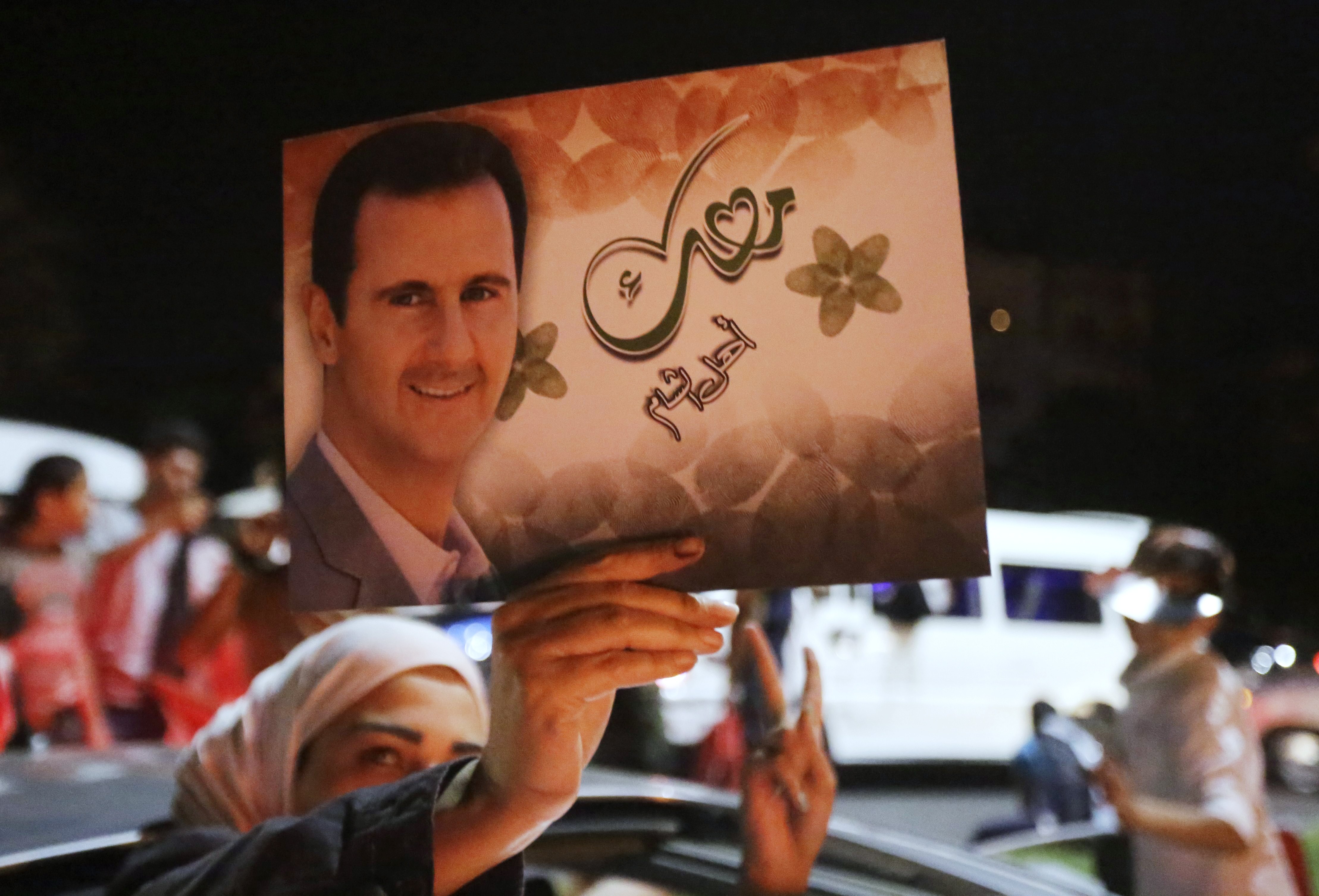 A woman holds a picture of re-elected Syrian President Bashar Assad as she celebrates in Damascus after he was announced as the winner of the presidential election on June 4, 2014. (Joseph Eid—AFP/Getty Images)